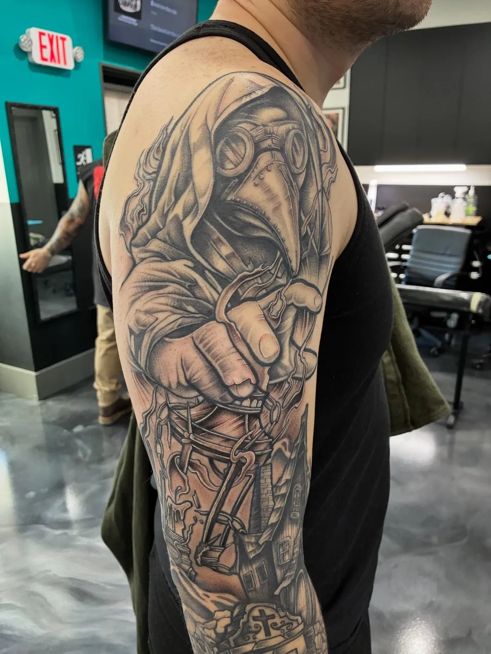 Hooded figure realism tattoo on the upper arm by Adam Silfies
