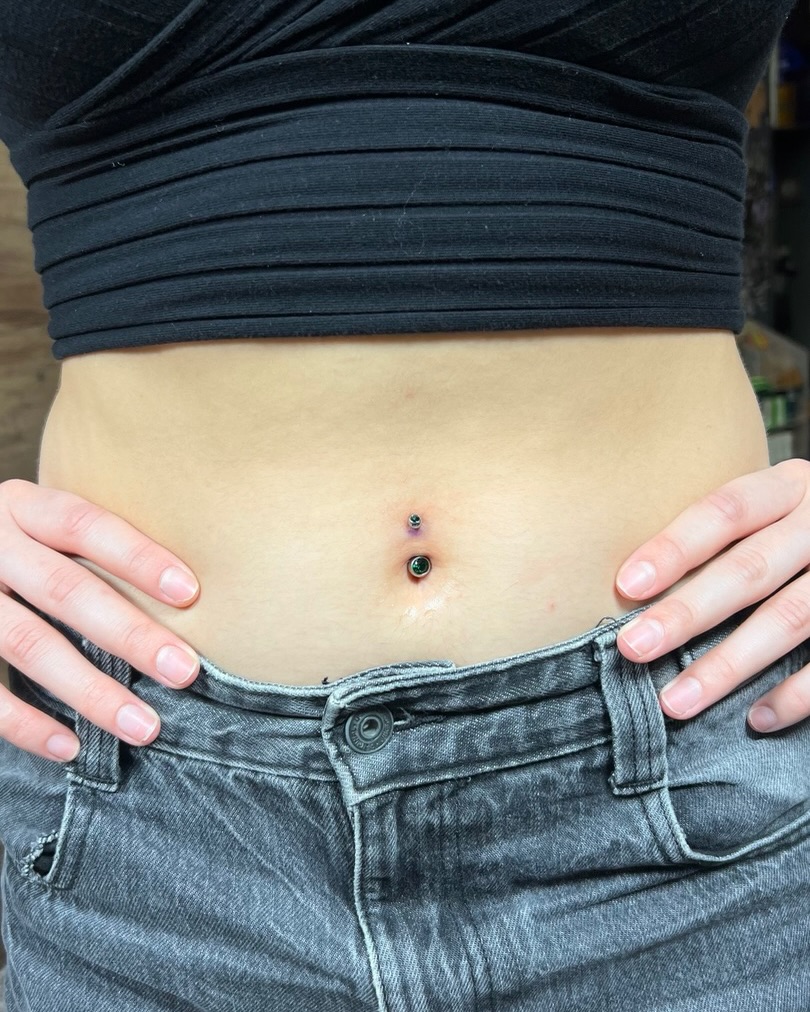 Navel piercing black and grey tattoo on the torso by Asap tattoo