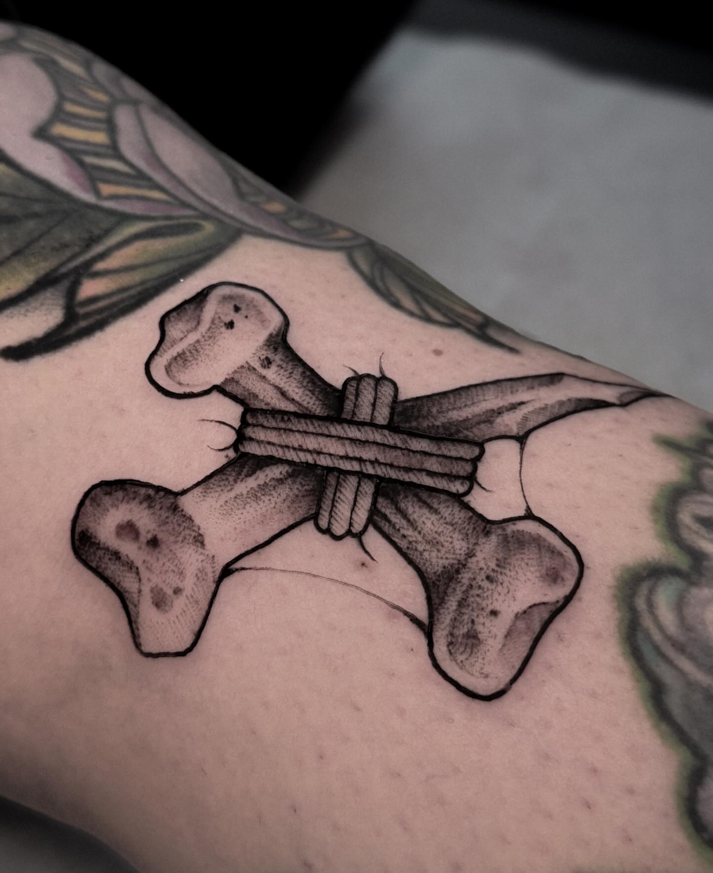 Crossbones black and grey tattoo on the forearm by La Hyene