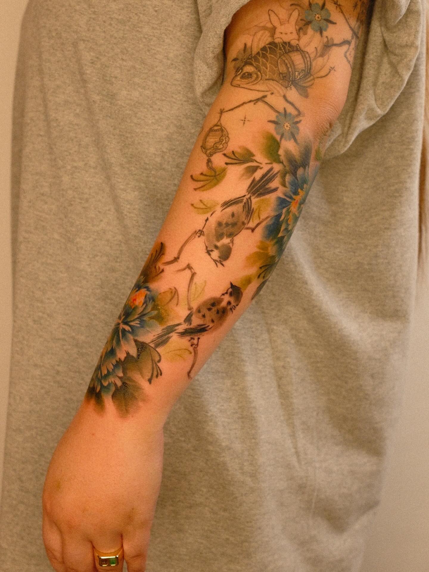 Birds and flowers watercolor tattoo on the forearm by Nicki Yến