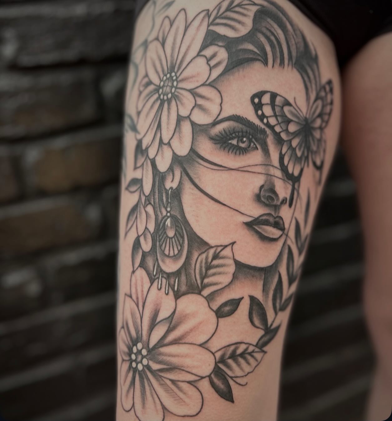 Woman with flowers and butterfly realism tattoo on the thigh by Dylan O'Quin