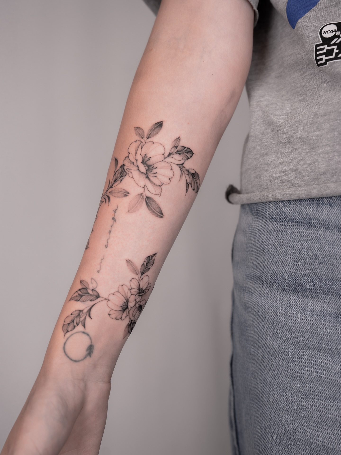 Floral arrangement black and grey tattoo on the forearm by Leo Gao