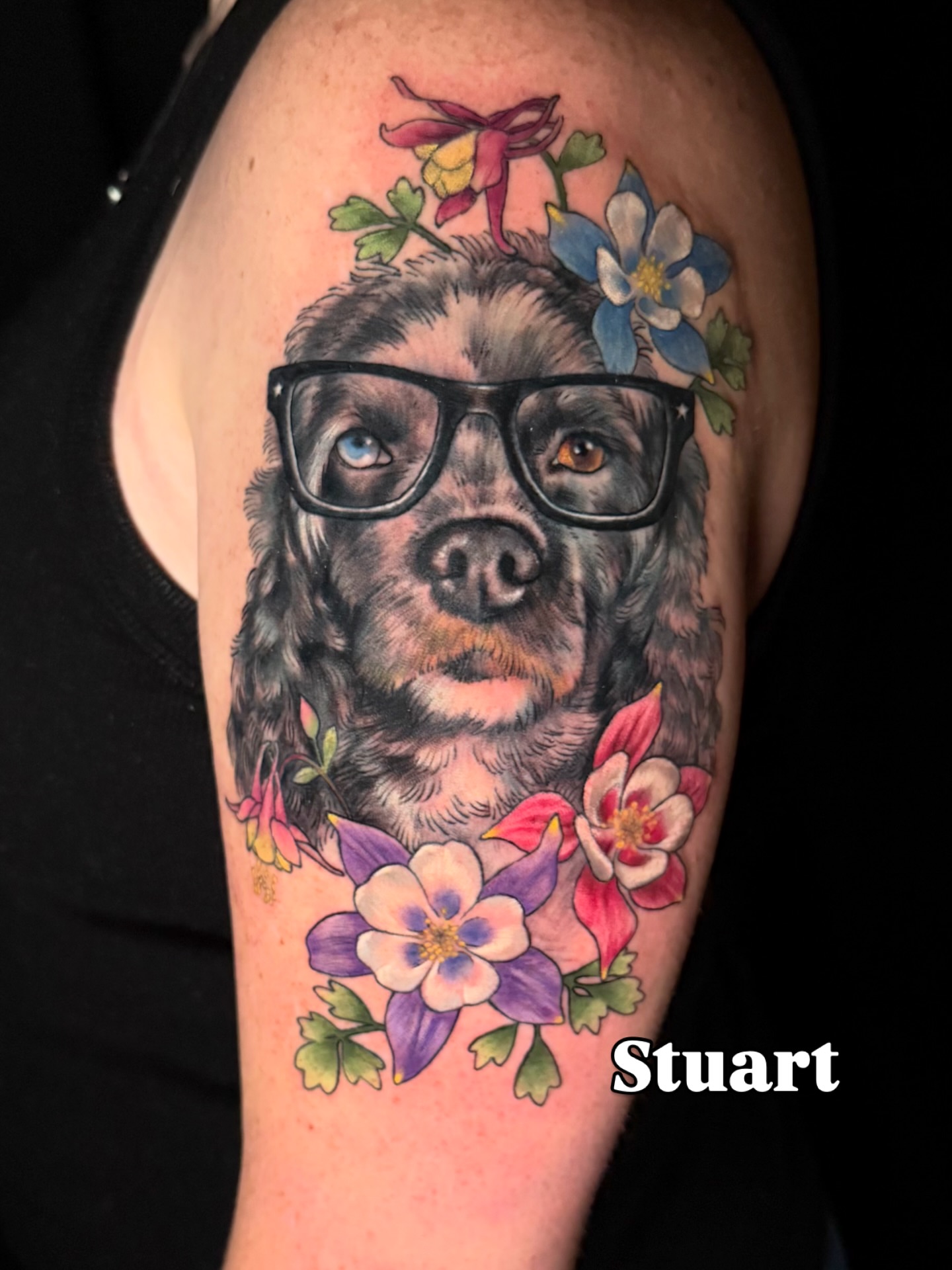 Dog wearing glasses realism tattoo on the upper arm by Christel Perkins