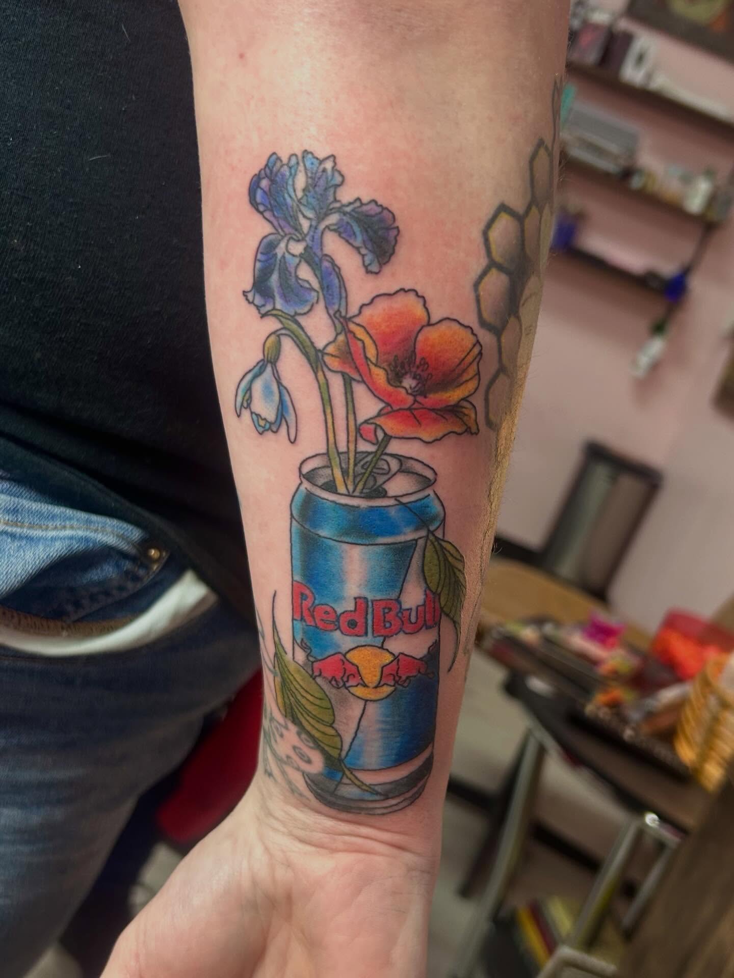 Flowers in Red Bull can realism tattoo on the forearm by Red✨, Gansevoort, New York
