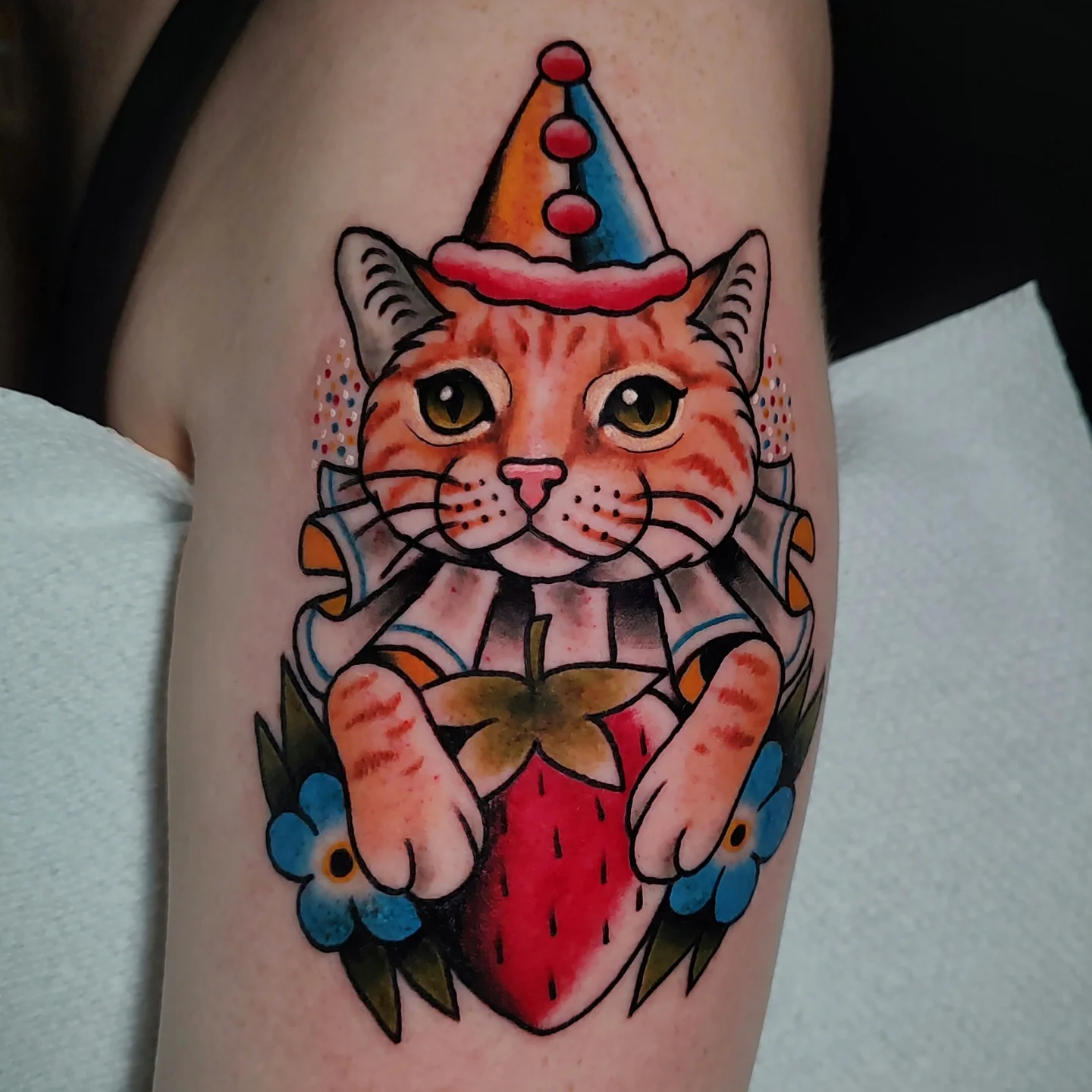Cat with party hat American traditional tattoo on the forearm by Hope Higgins