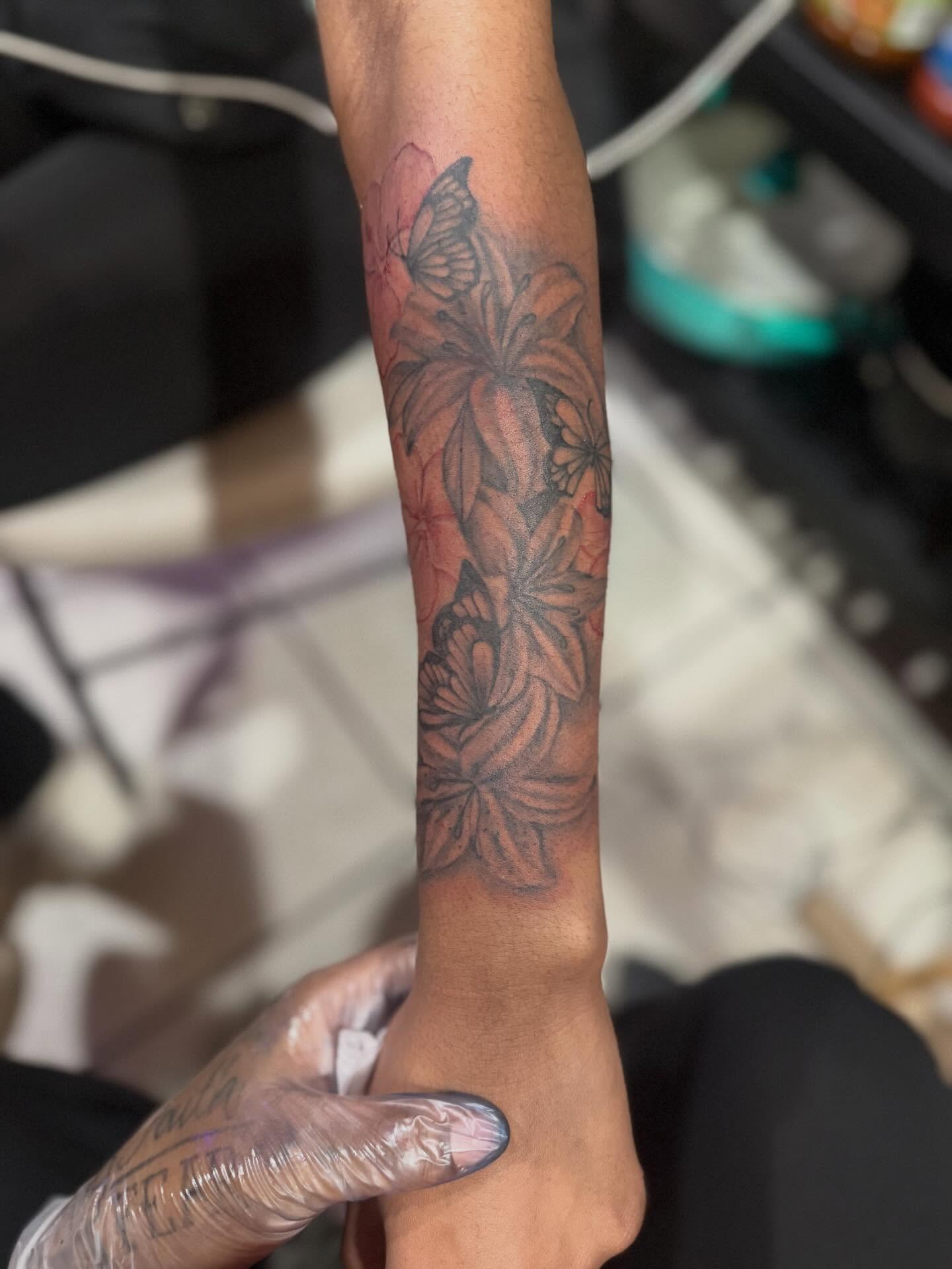 Flowers and butterflies black and grey tattoo on the forearm by Aja Marie