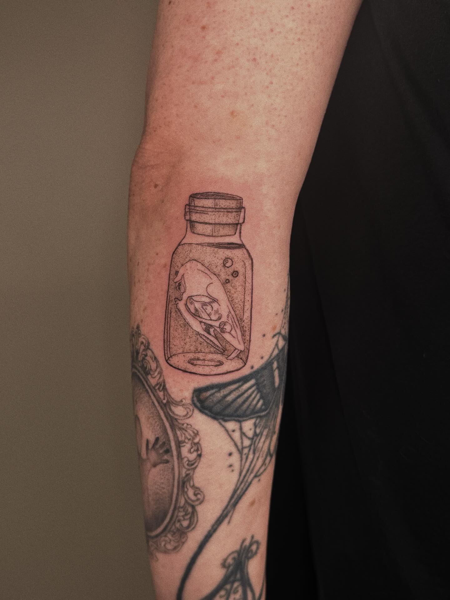Jar with fish dotwork tattoo on the forearm by Paulina Vazquez