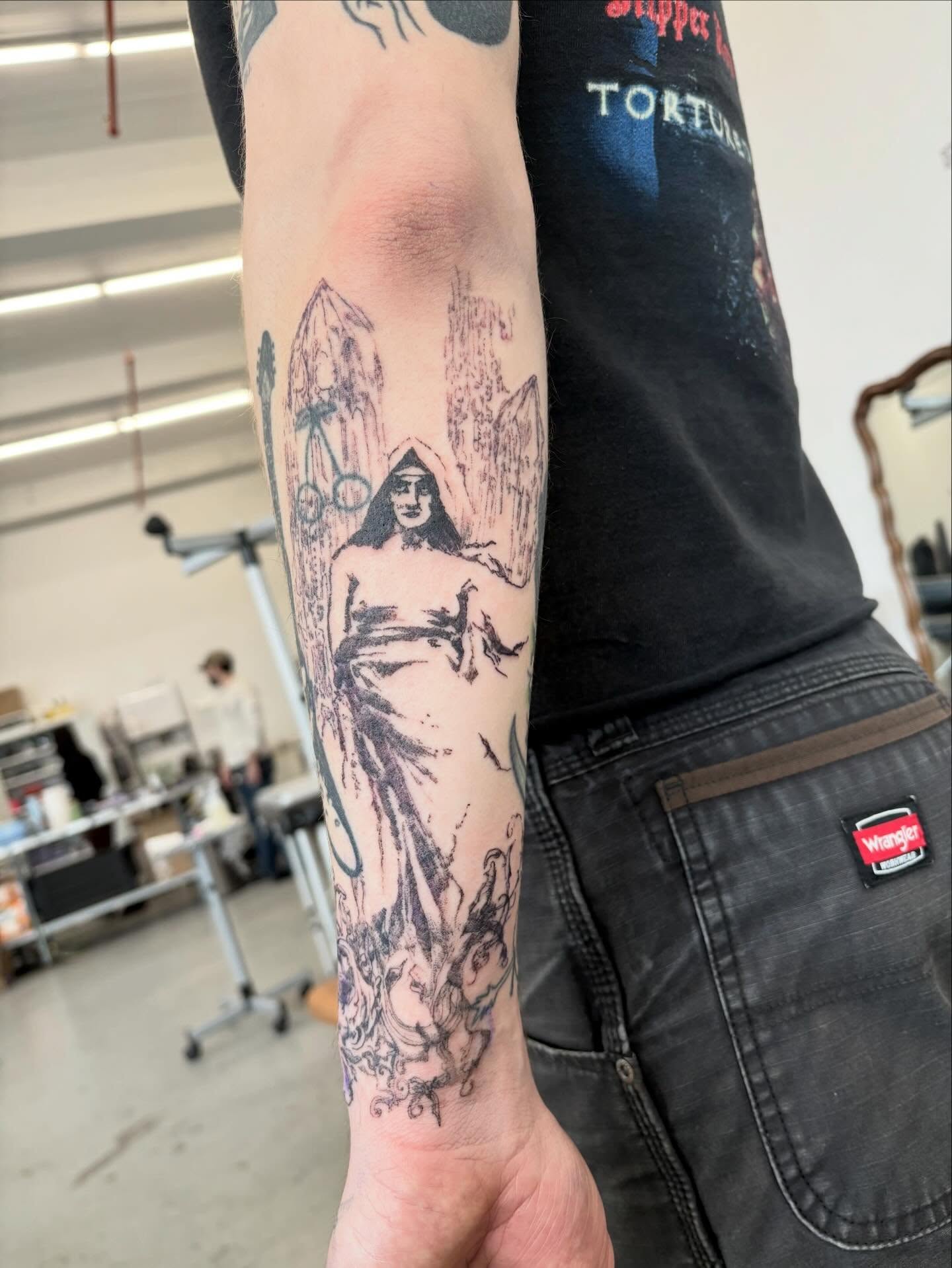 Woman with flowing robe black and grey tattoo on the forearm by madeline