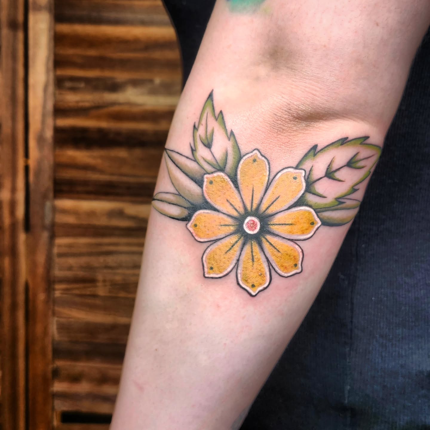 Yellow flower American traditional tattoo on the forearm by Kelly Zito