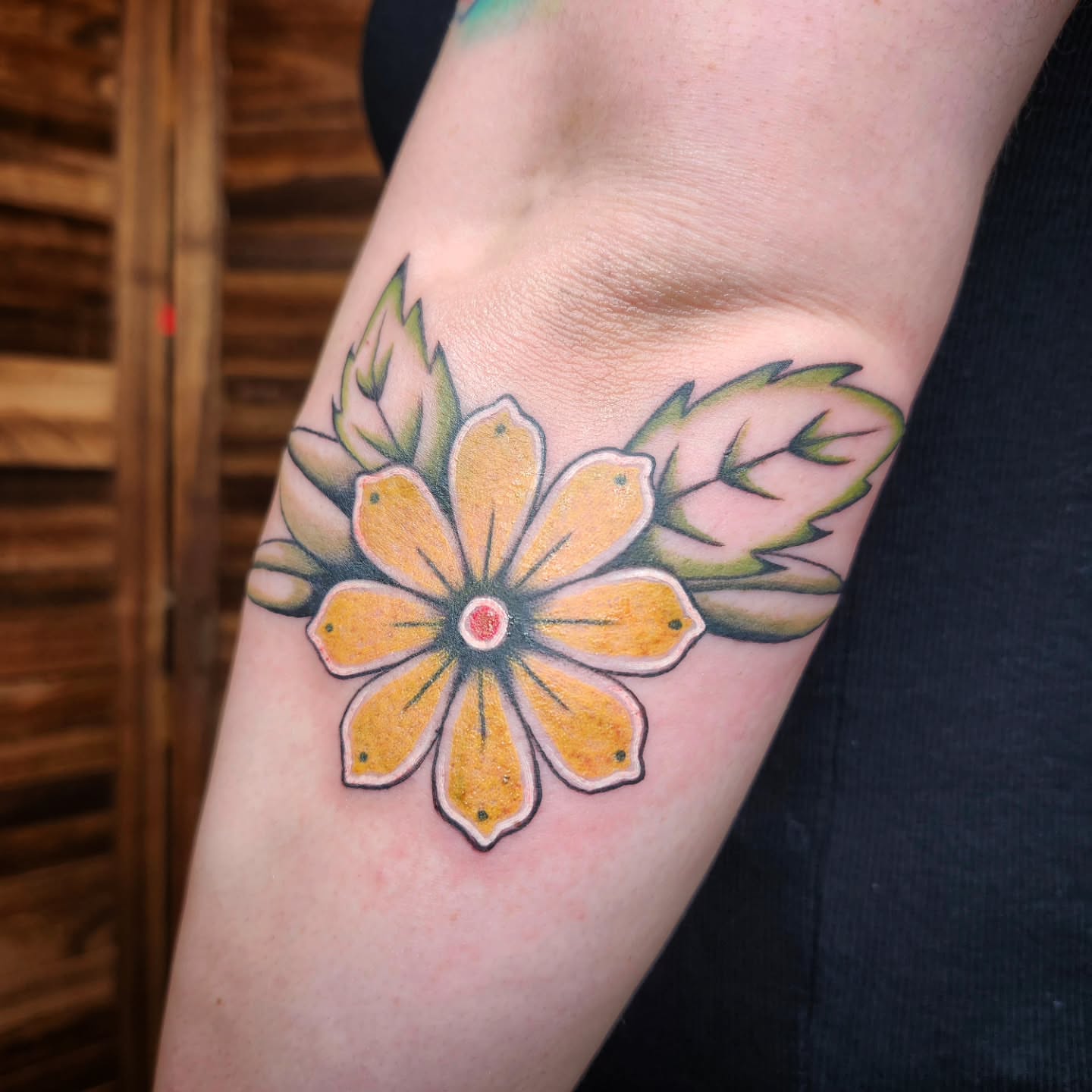 Yellow flower American traditional tattoo on the forearm by Kelly Zito