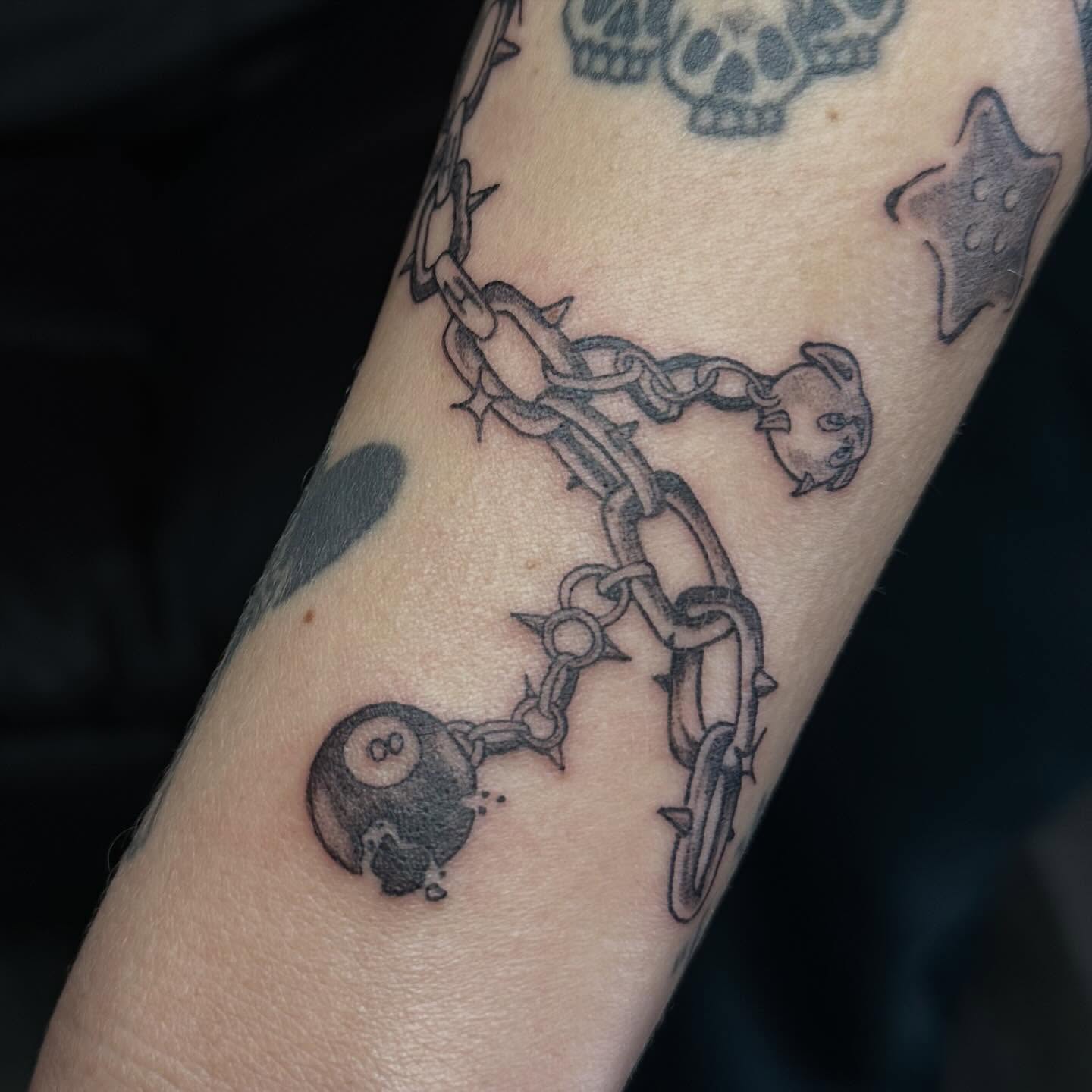 Chains and ball black and grey tattoo on the forearm by Maddie Neibert