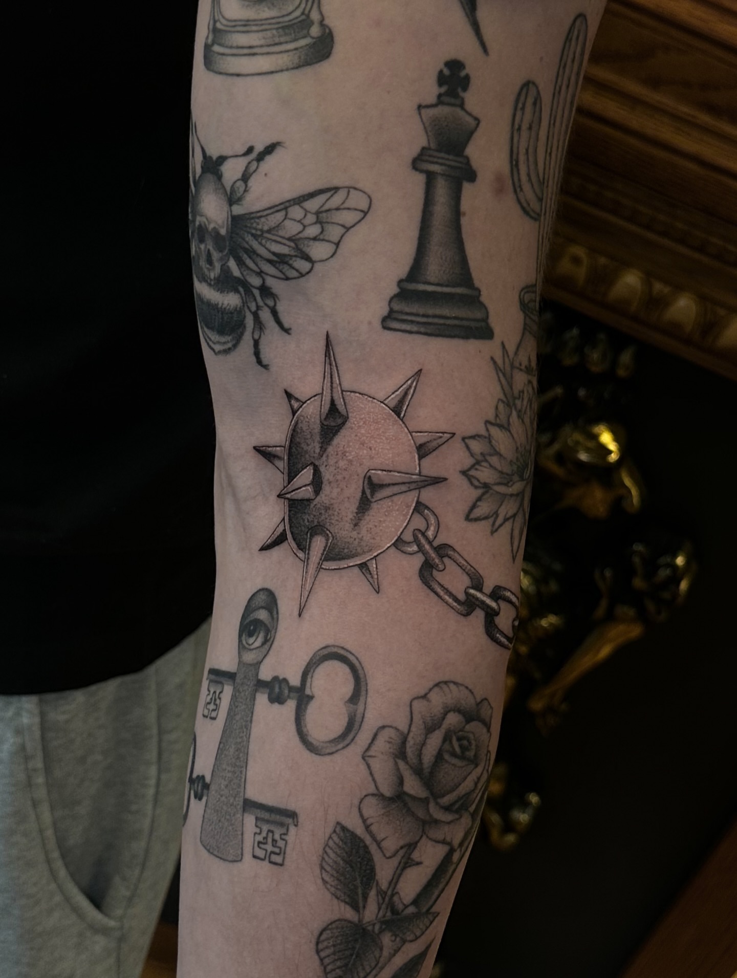Chess piece and bee black and grey tattoo on the forearm by Leo Fernandes, Danvers, Massachusetts