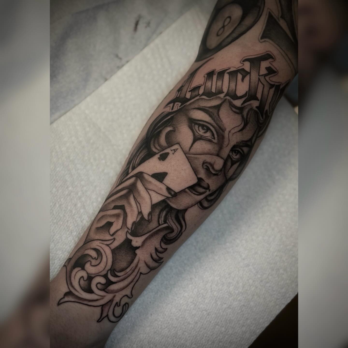 Woman with playing card black and grey tattoo on the forearm by Alyssa Deeghan