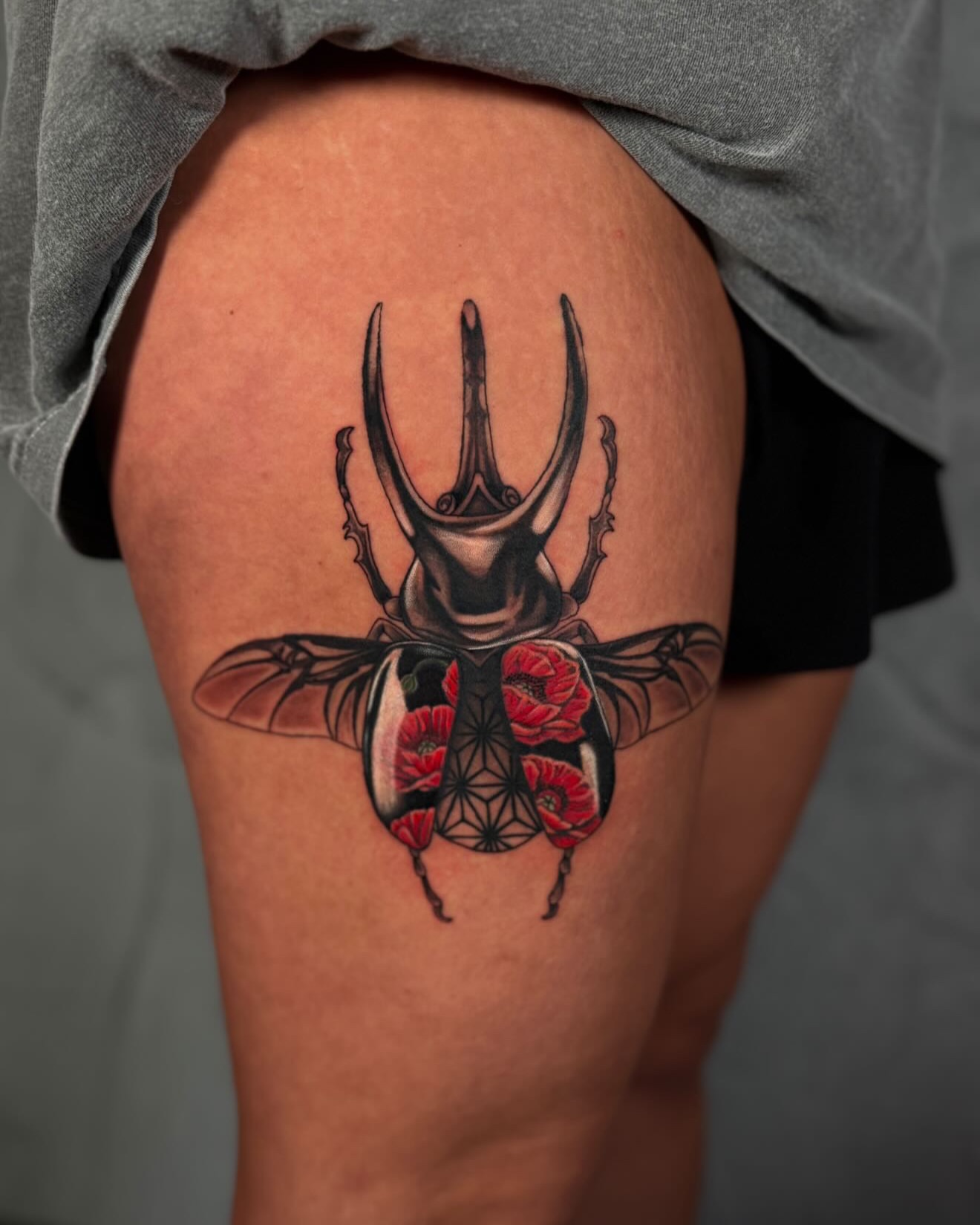Scarab beetle with poppies geometric tattoo on the thigh by Ethan Lund