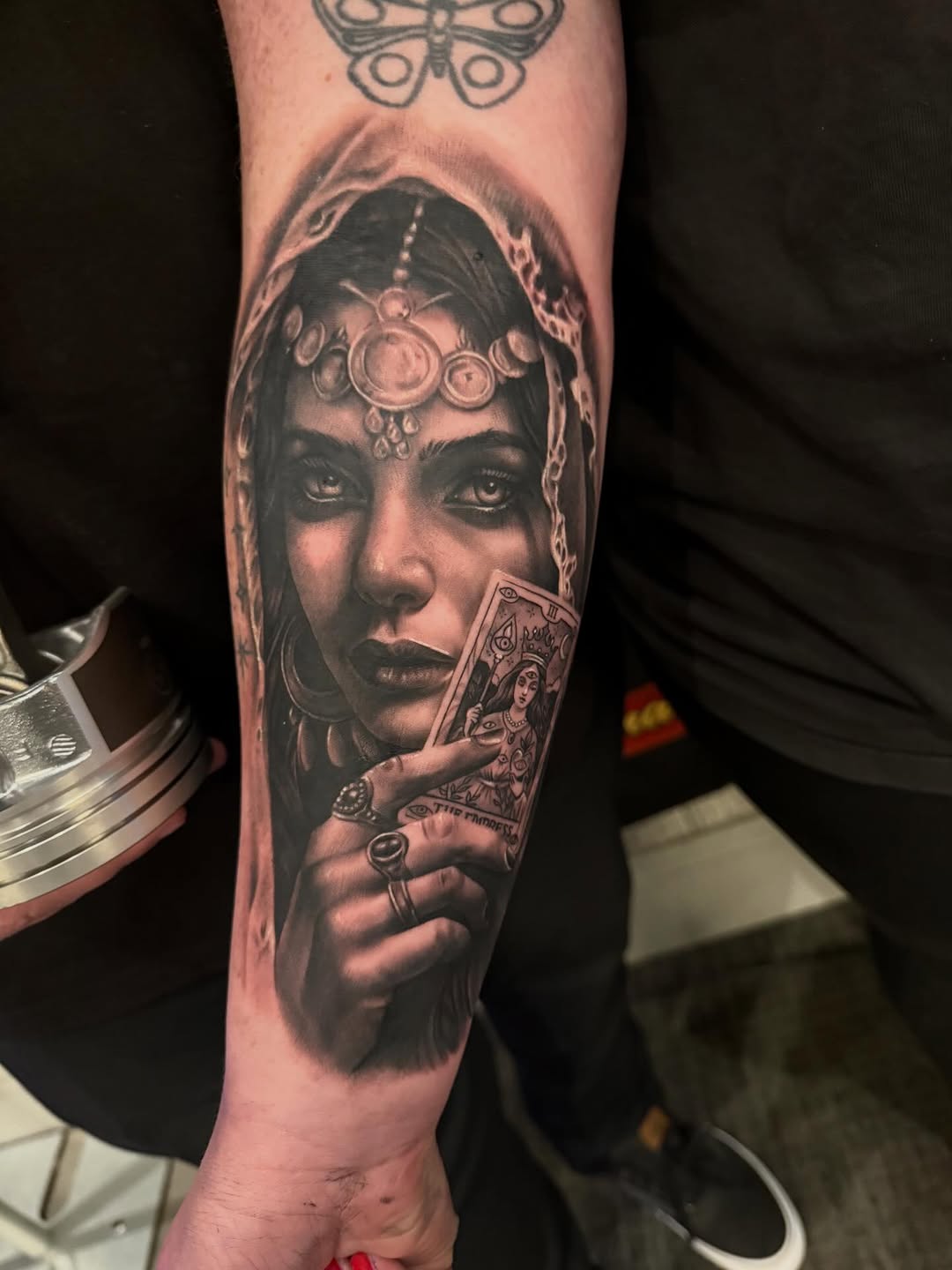 Woman holding tarot card realism tattoo on the forearm by Aaron Watson