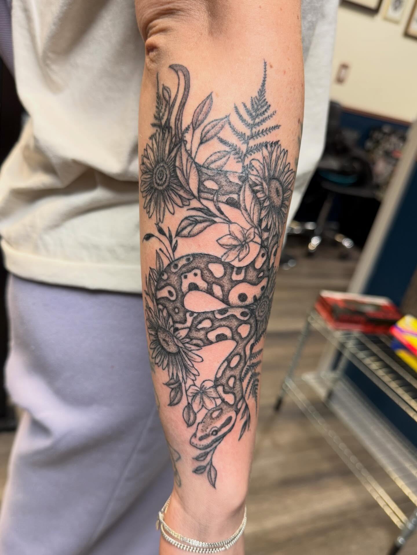 Snake and flowers black and grey tattoo on the forearm by Elena