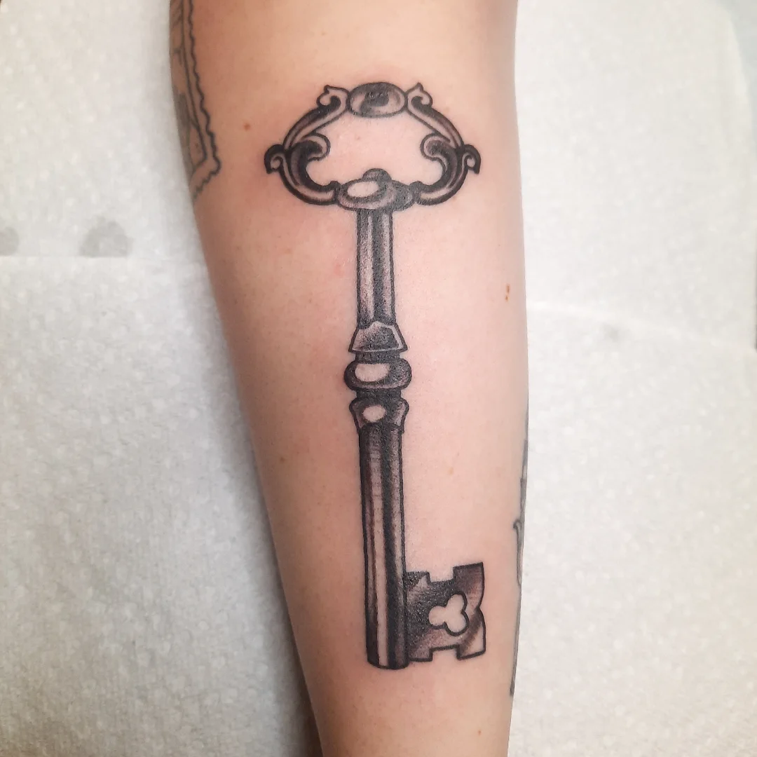 Key black and grey tattoo on the forearm by Kaetlyn