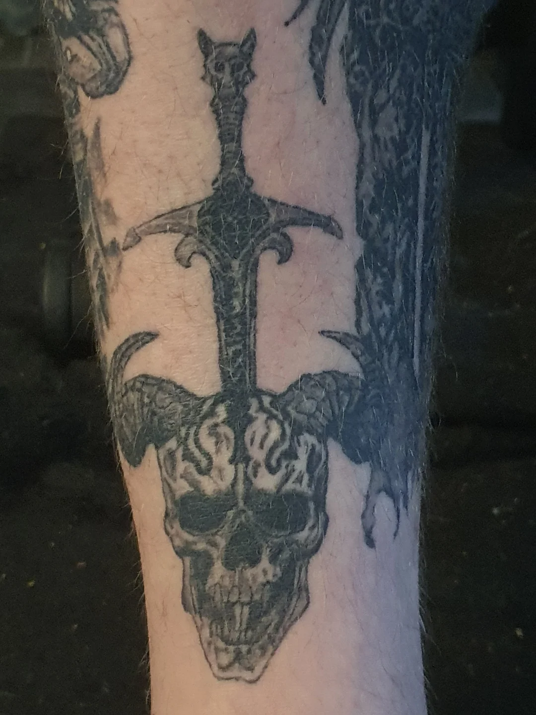 Skull and sword dark realism tattoo on the forearm by Artful Ink