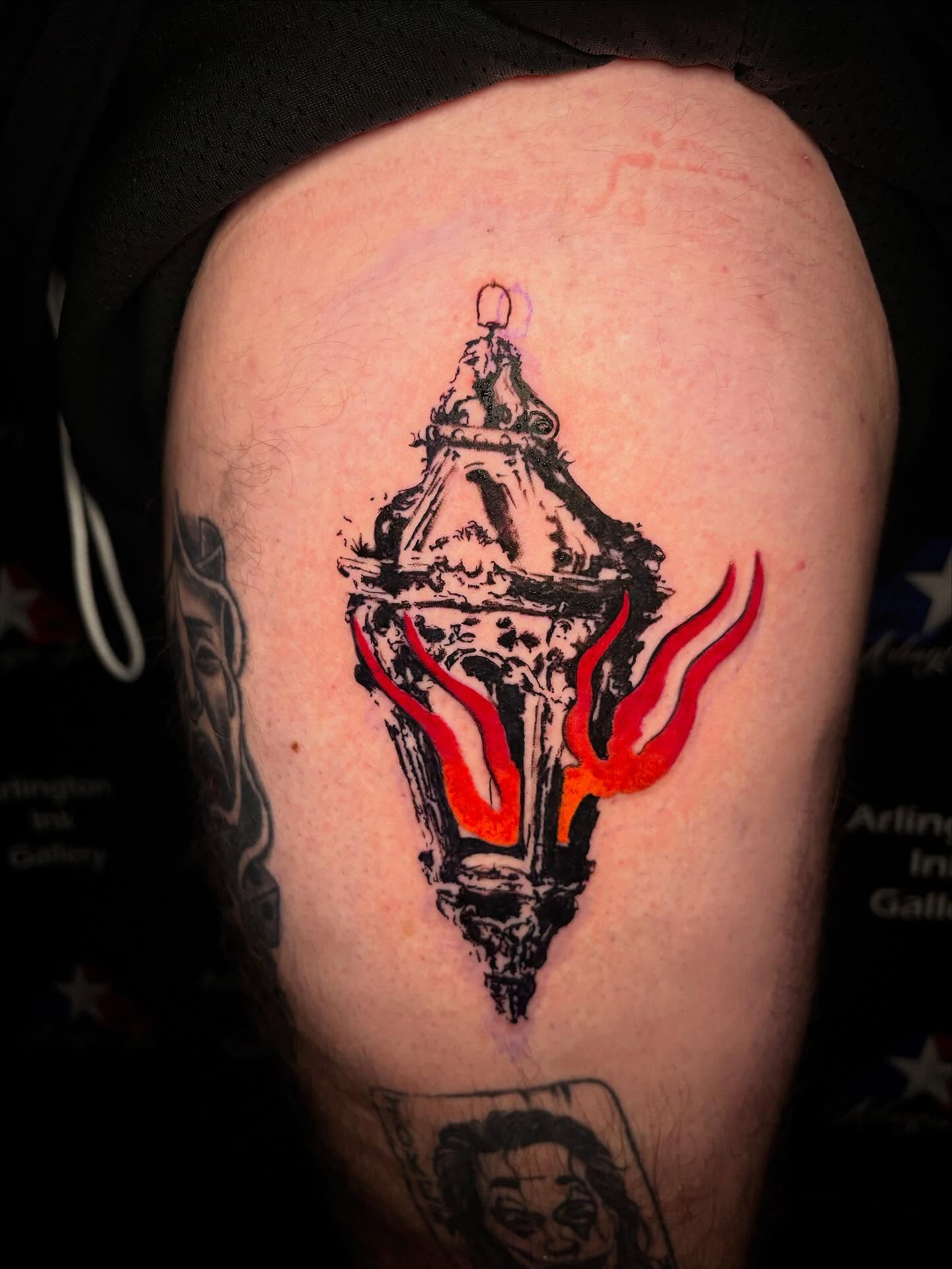Street lamp with flames black and grey tattoo on the shoulder by Haley Byers