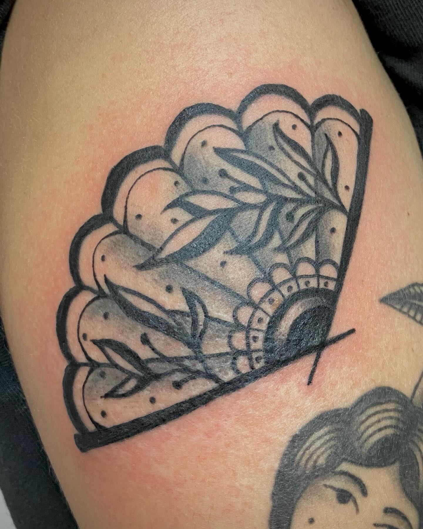 Fan with leaves black and grey tattoo on the shoulder by Ty Elias