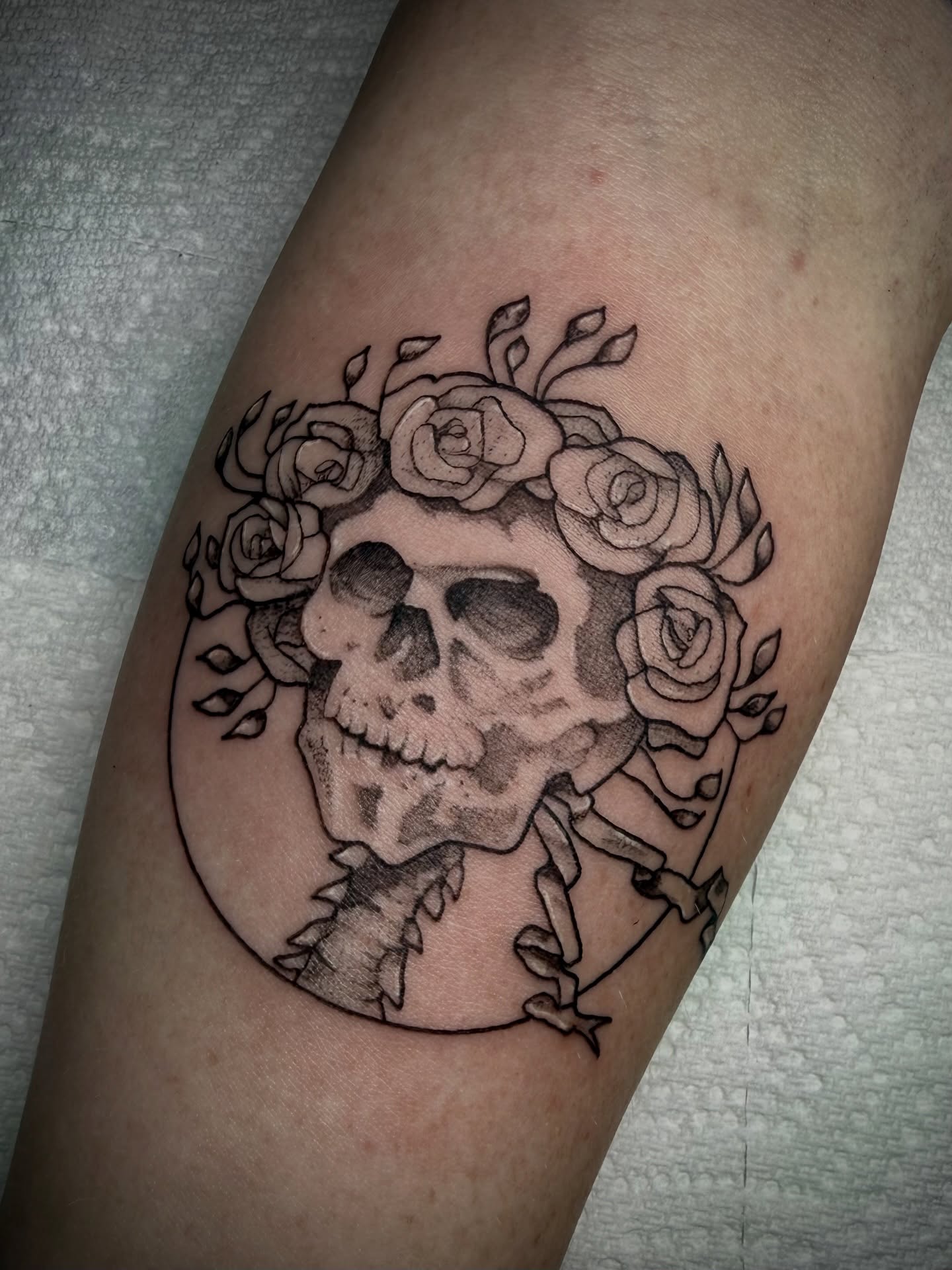 Skull with roses black and grey tattoo on the forearm by Ashley Laine Evans