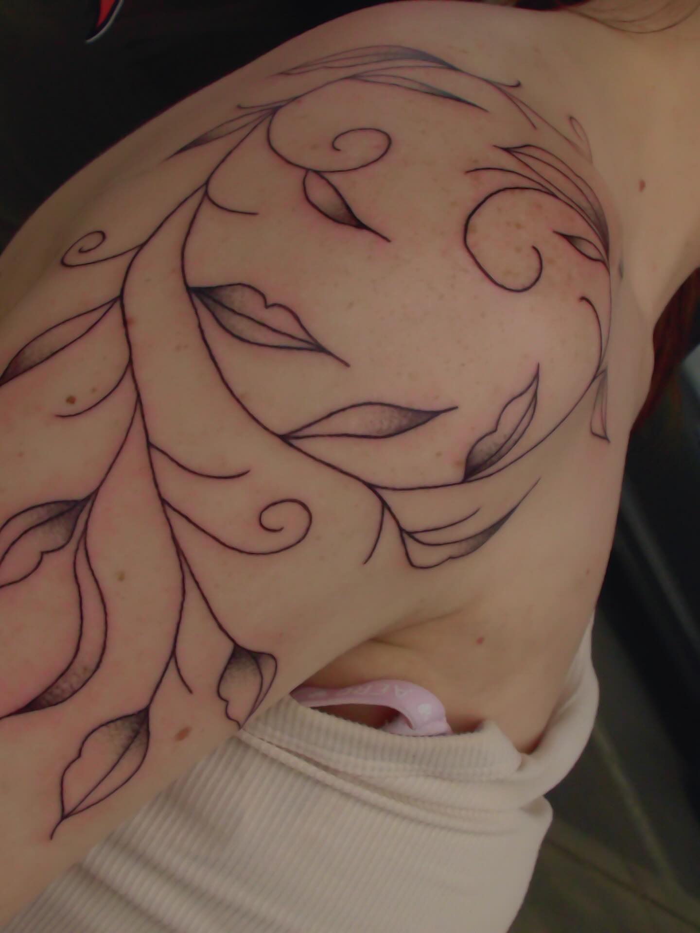 Abstract face fine line tattoo on the shoulder by zoie rozay hannah