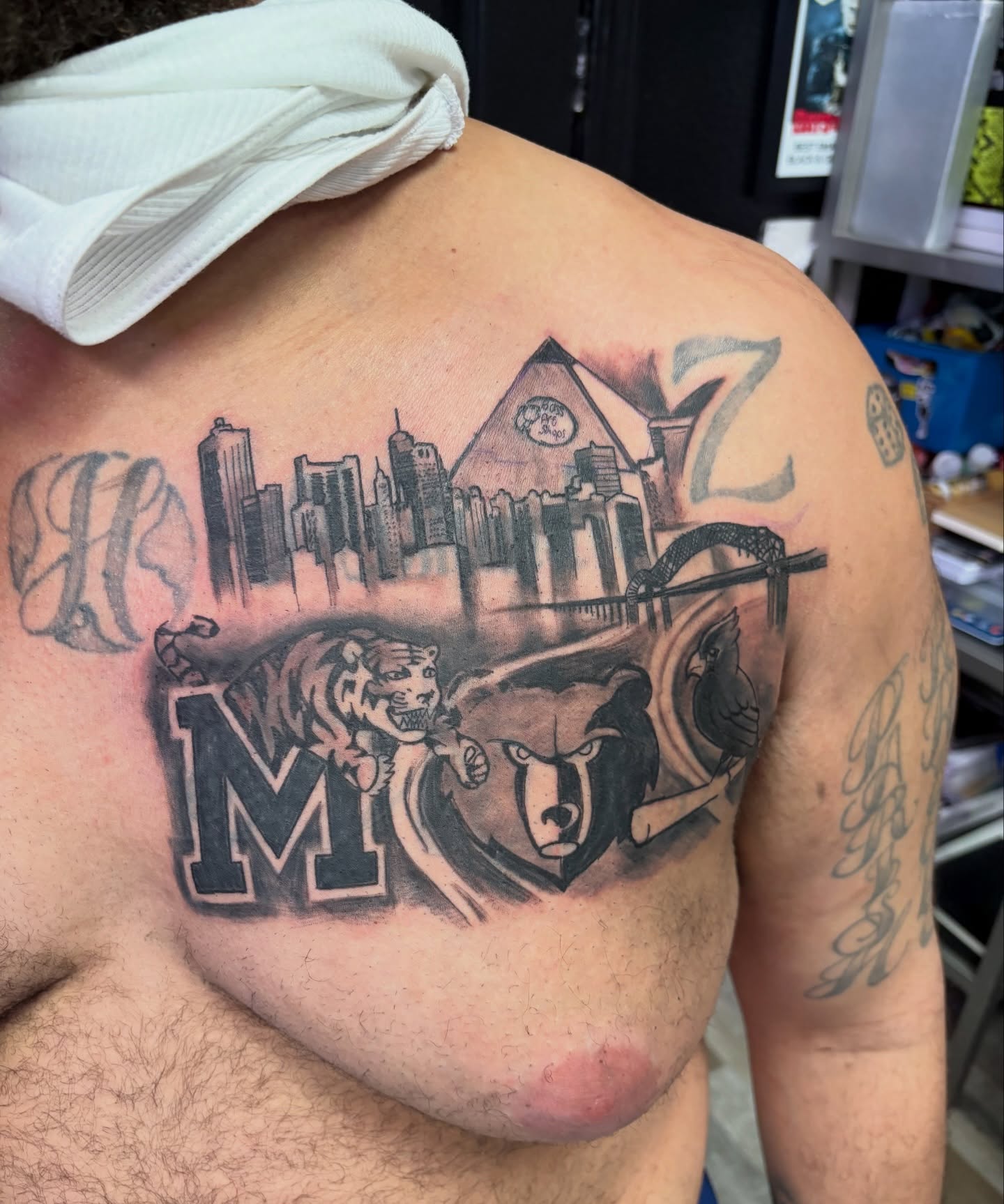 Cityscape with sports logos black and grey tattoo on the chest by Tyler Cooper, Las Vegas, Nevada