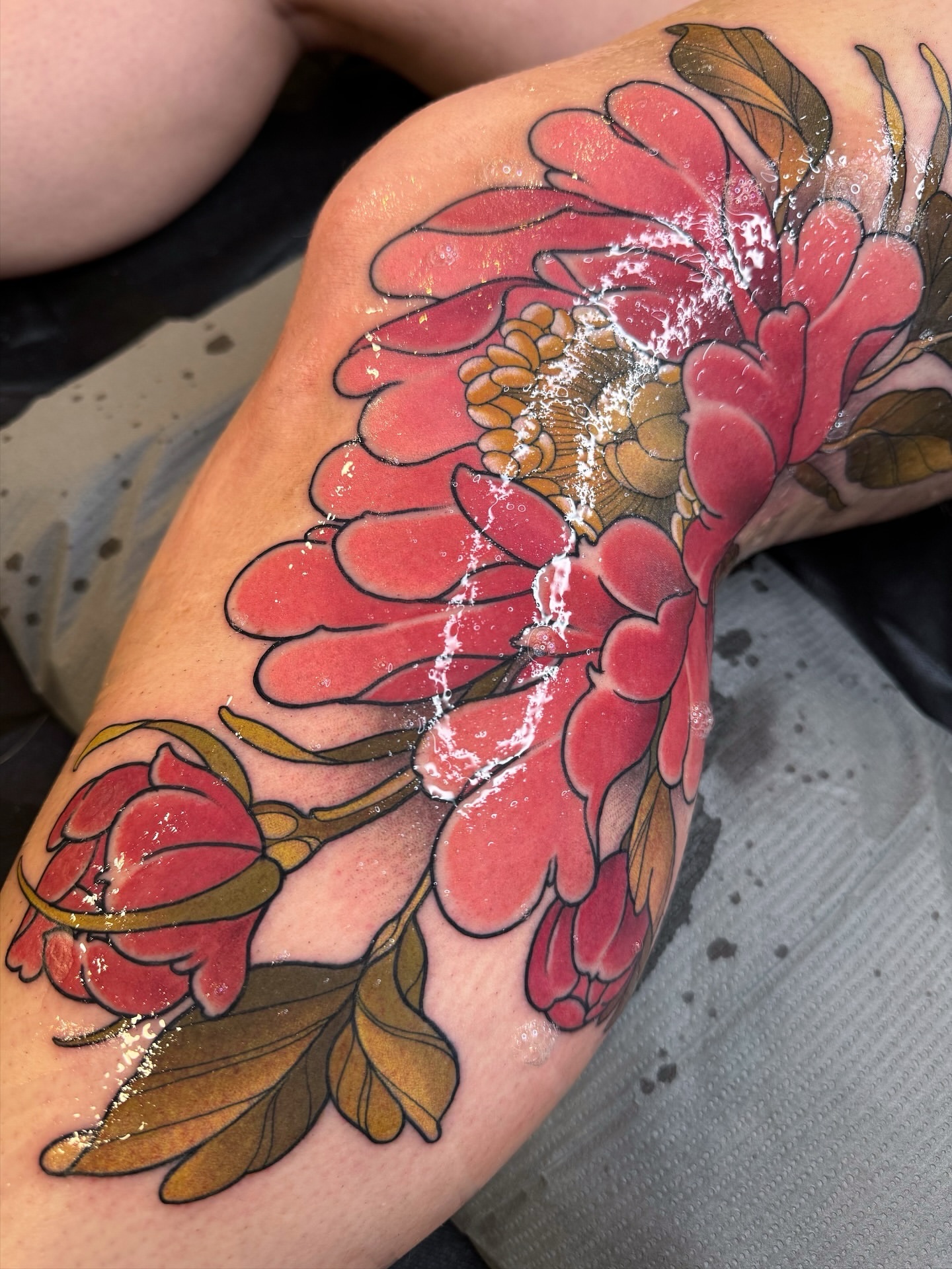 Peony flowers American traditional tattoo on the thigh by Anne Cornelson