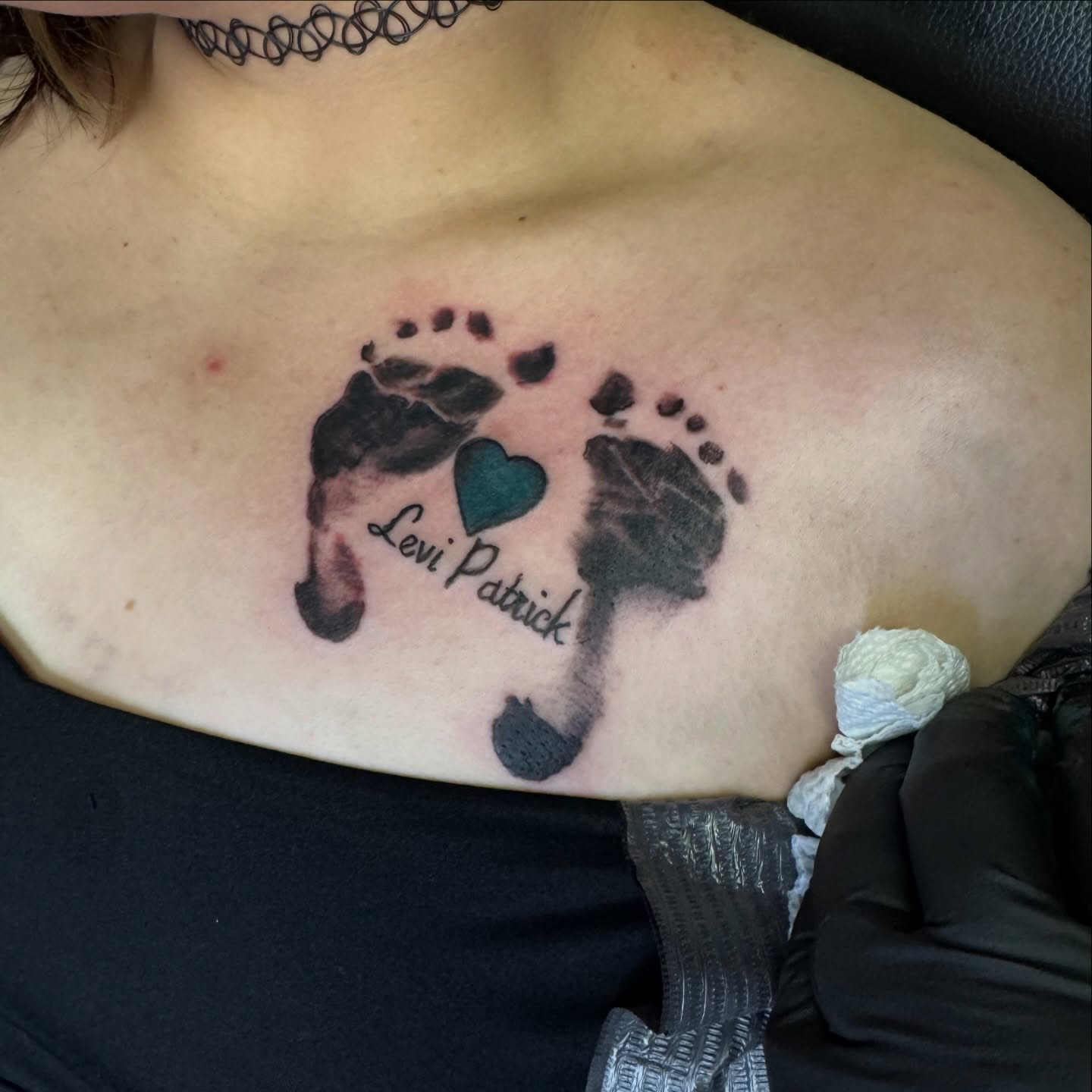 Baby footprints and heart dotwork tattoo on the chest by Bob Howdy