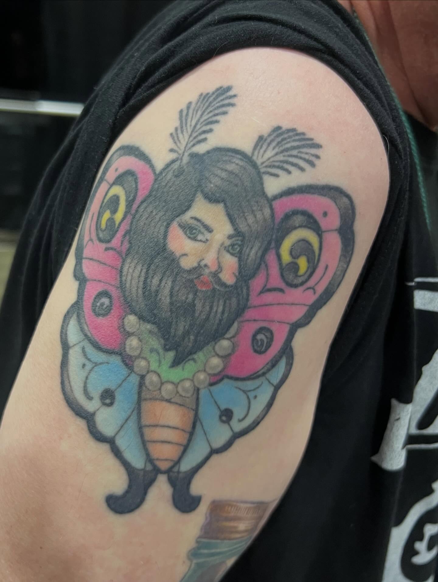 Bearded man with butterfly American traditional tattoo on the shoulder by Katie Ann Tattoos