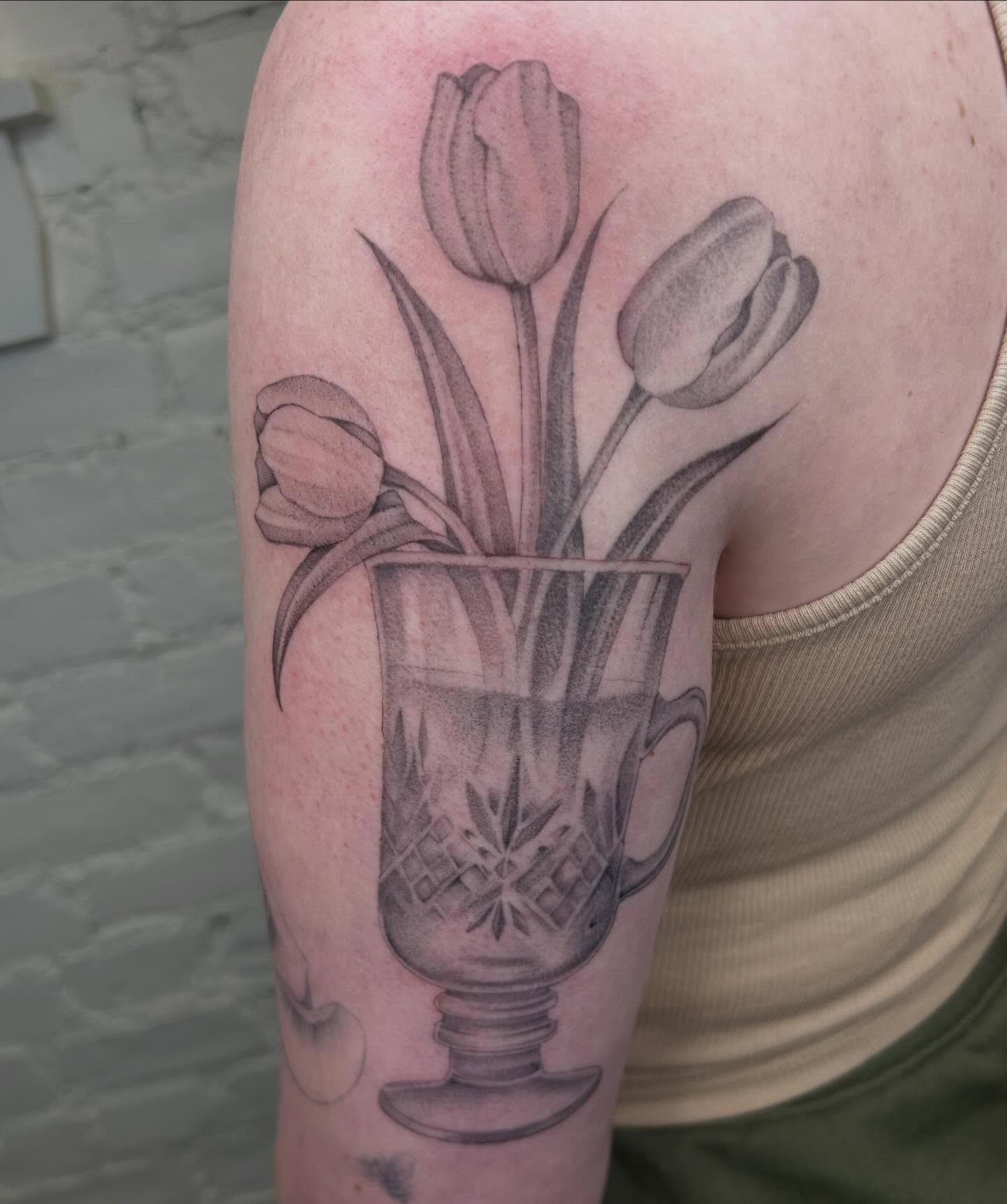 Tulips in a glass dotwork tattoo on the upper arm by Olivia Fox