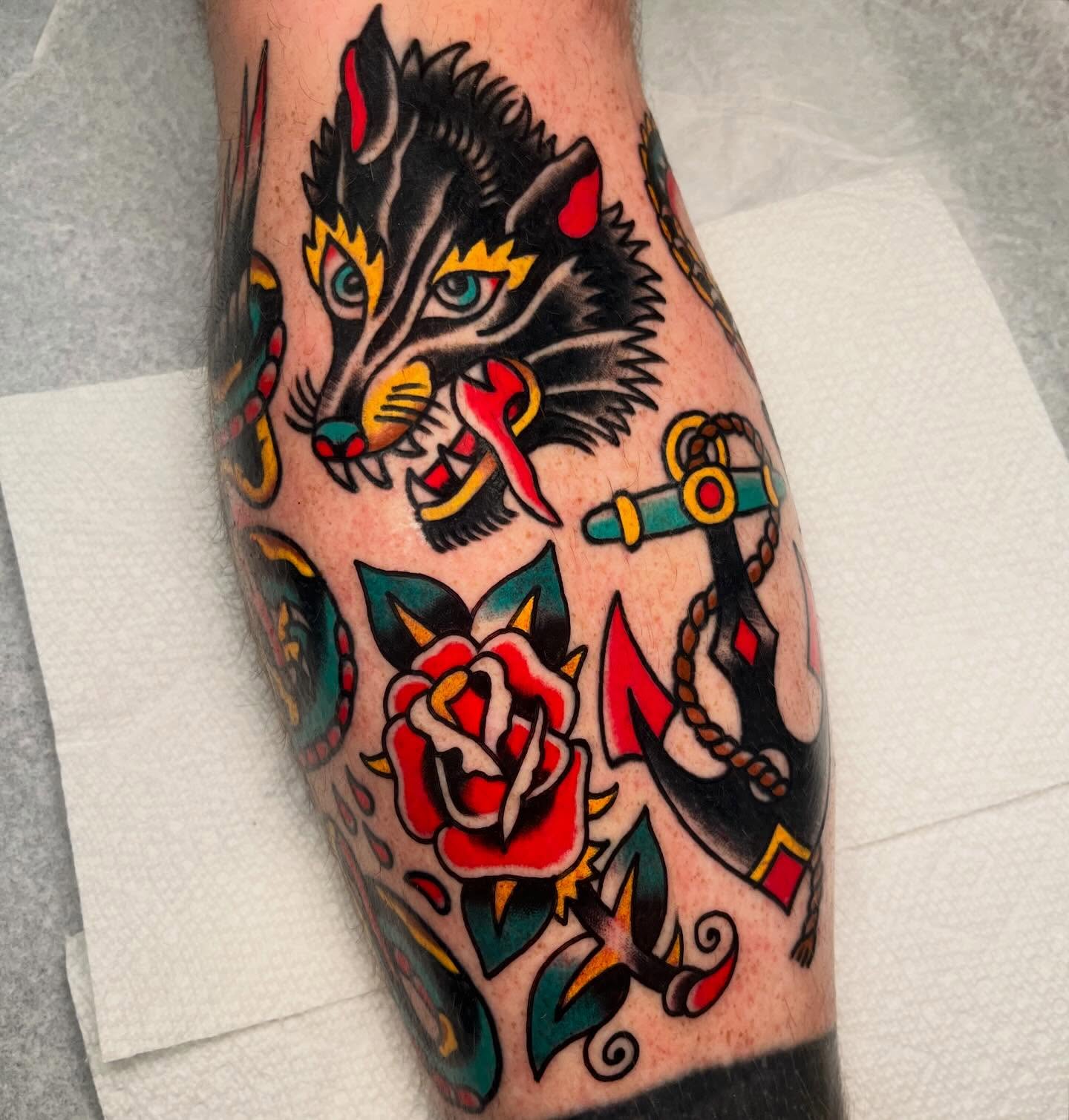 Wolf and anchor American traditional tattoo on the calf by Rizzo
