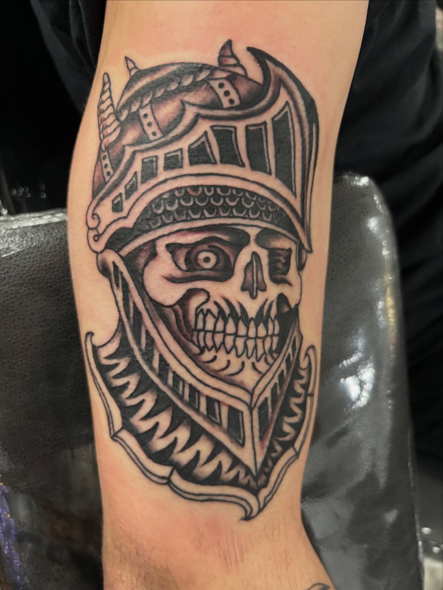 Skull wearing helmet American traditional tattoo on the forearm by Miklo Montoya