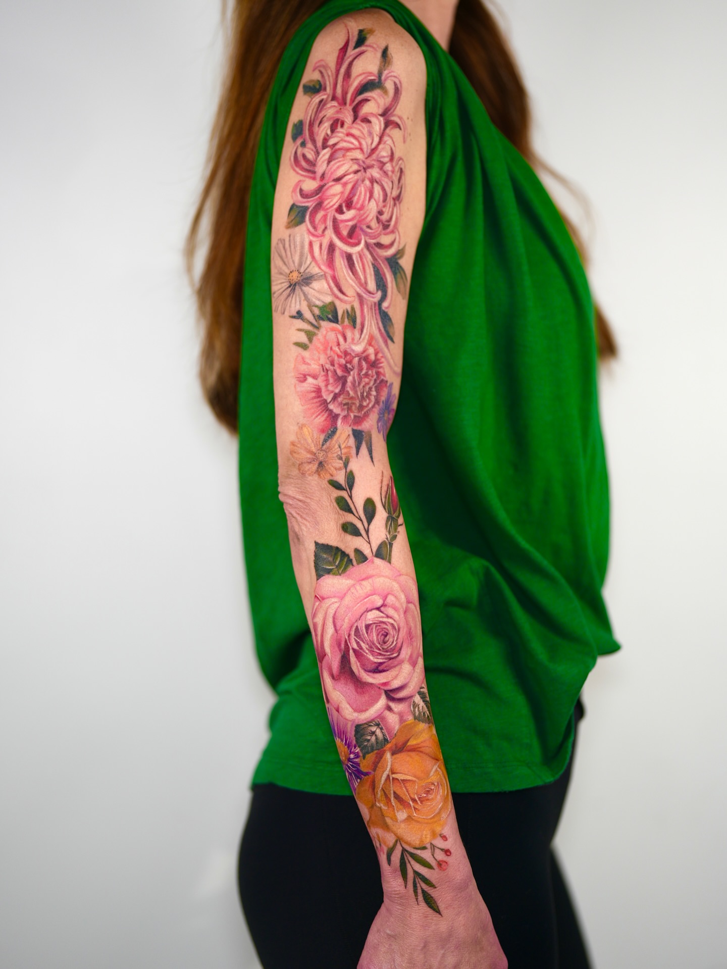 Floral bouquet realism tattoo on the upper arm by Henry
