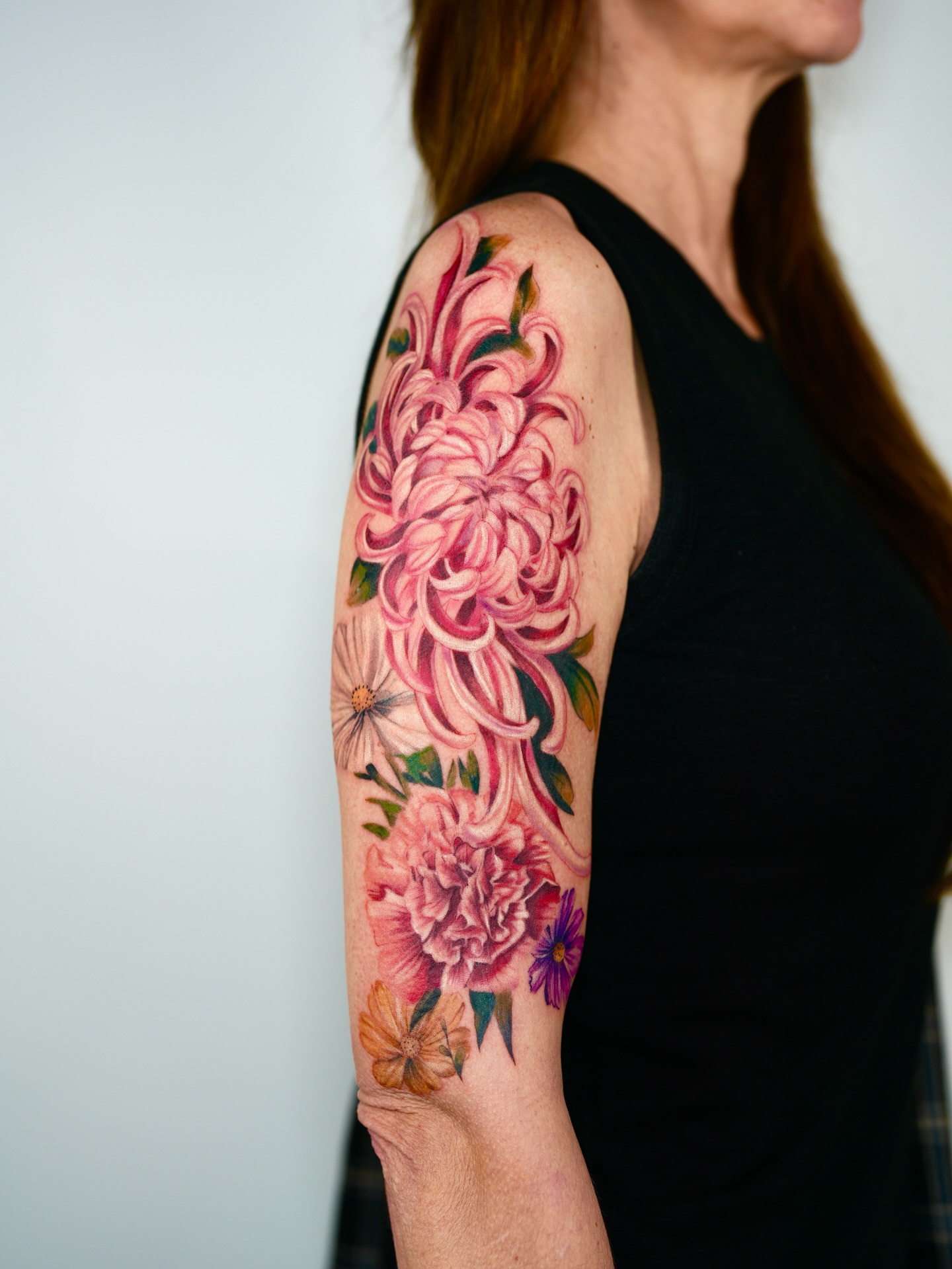 Floral bouquet realism tattoo on the upper arm by Henry