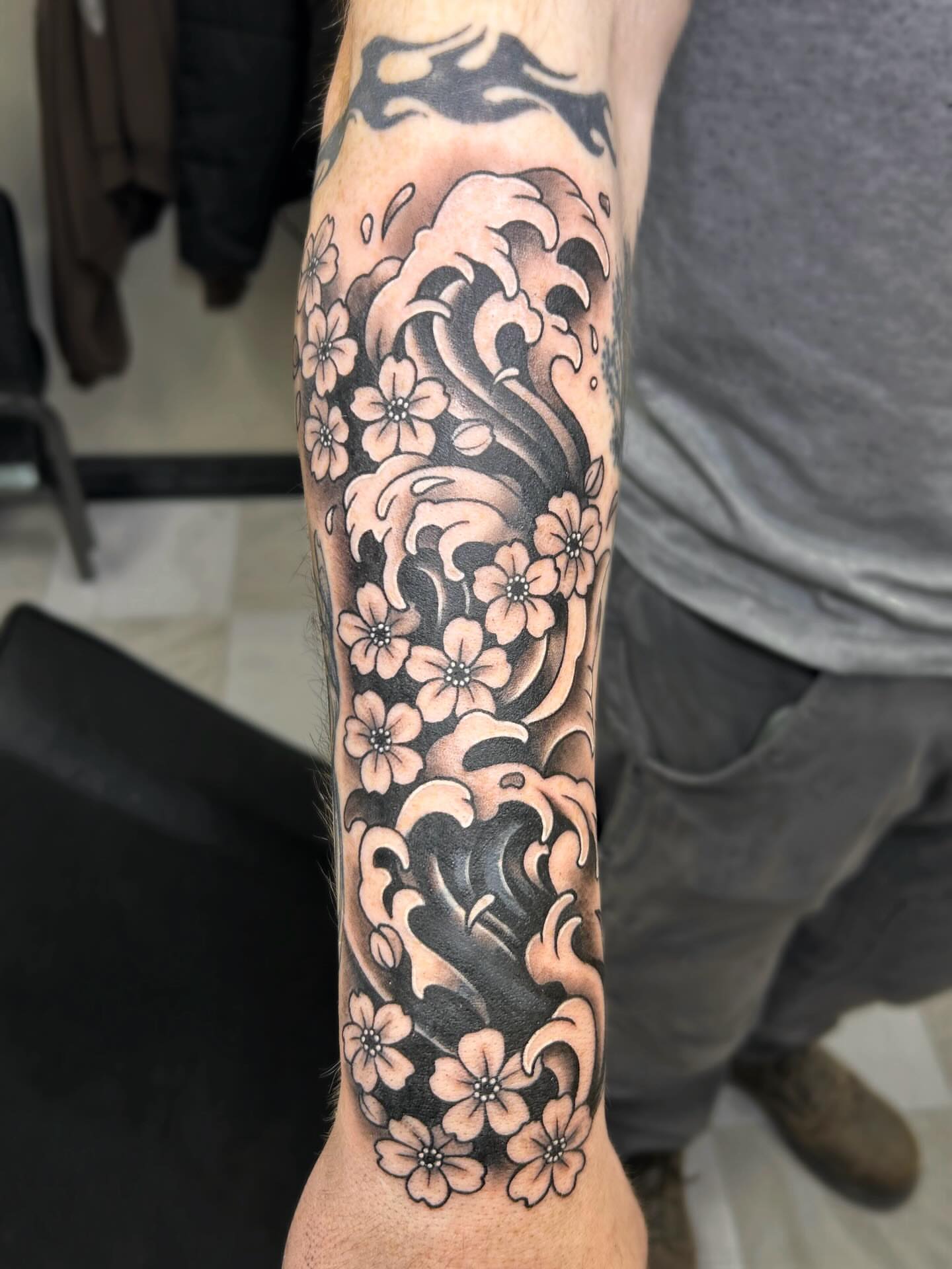 Wave and cherry blossoms japanese irezumi tattoo on the forearm by kuna ink