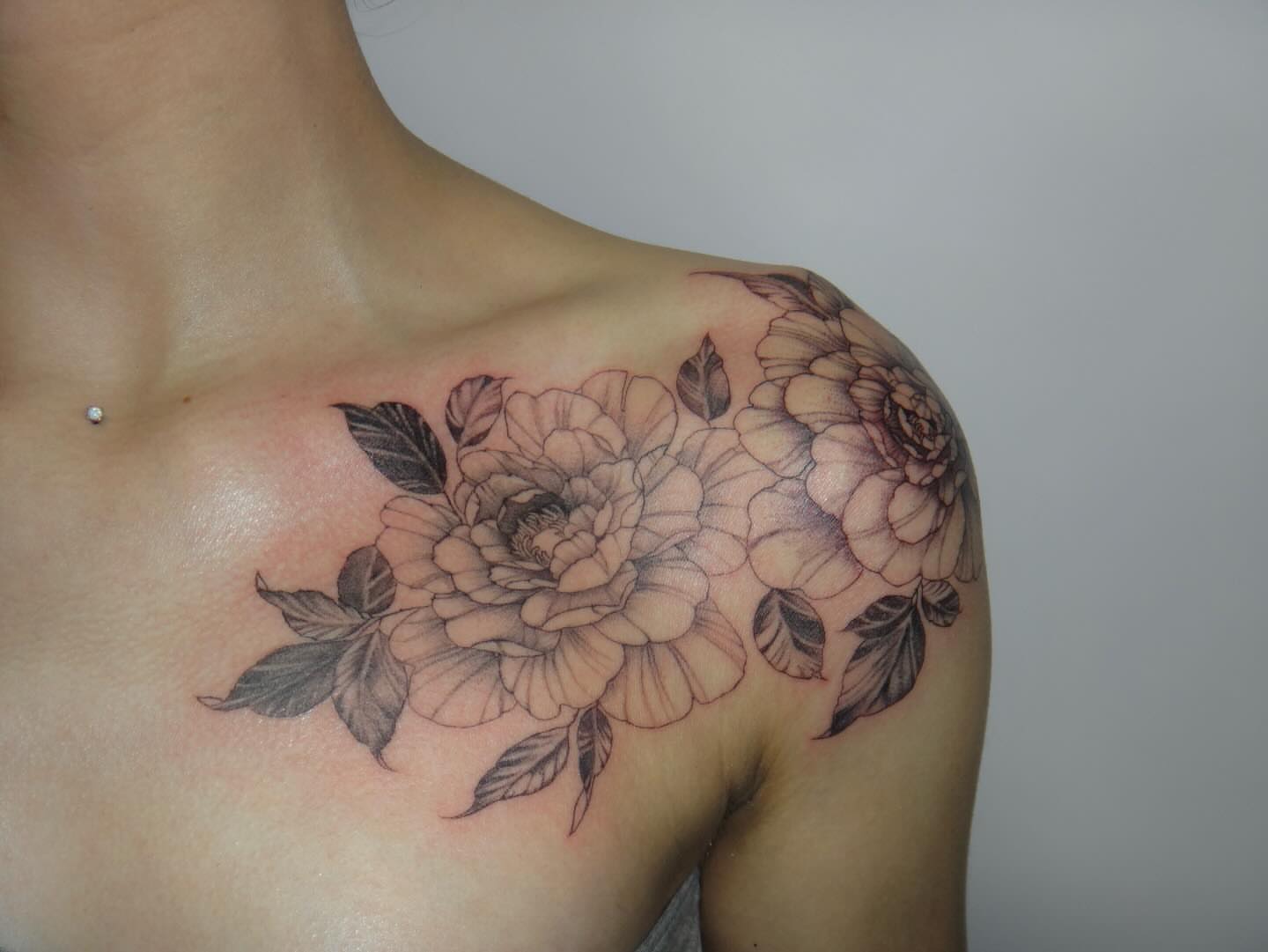 Floral bouquet black and grey tattoo on the shoulder by Nevaeh tattoo artist