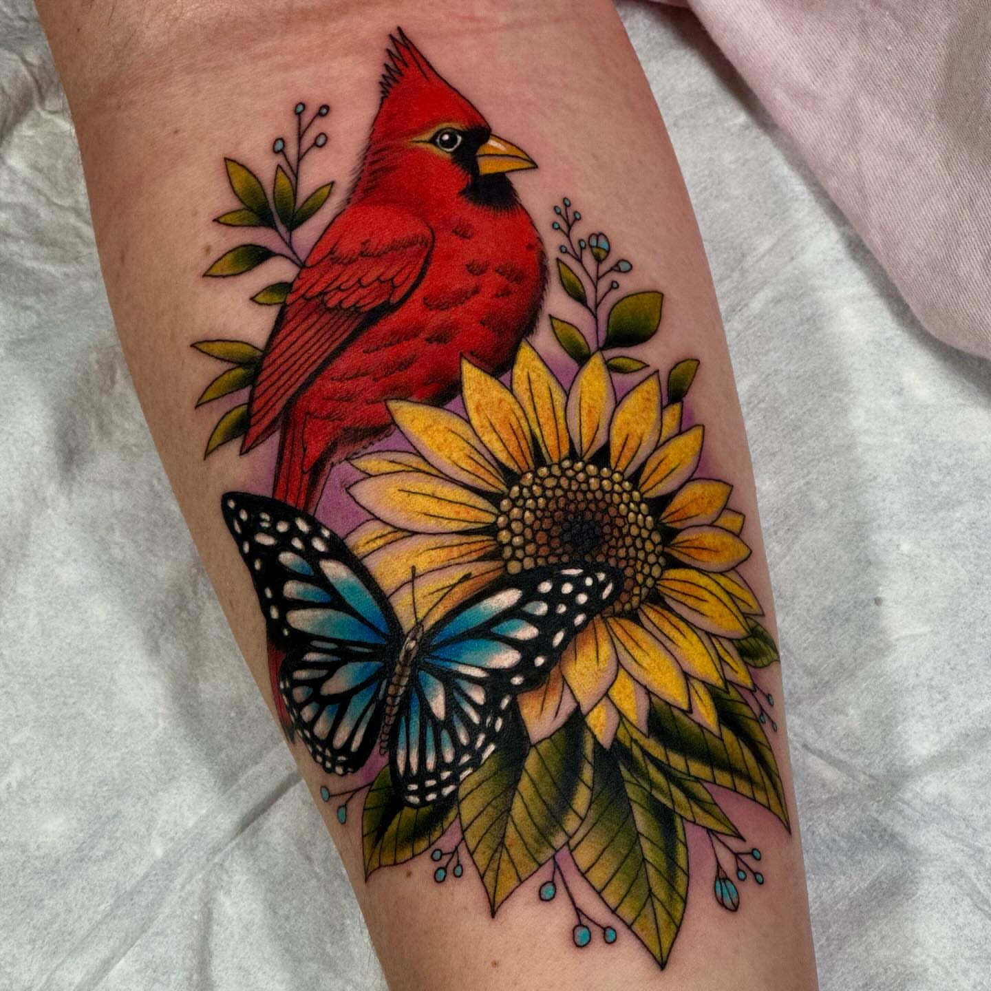 Cardinal, sunflower, butterfly realism tattoo on the forearm by Dylan Curry