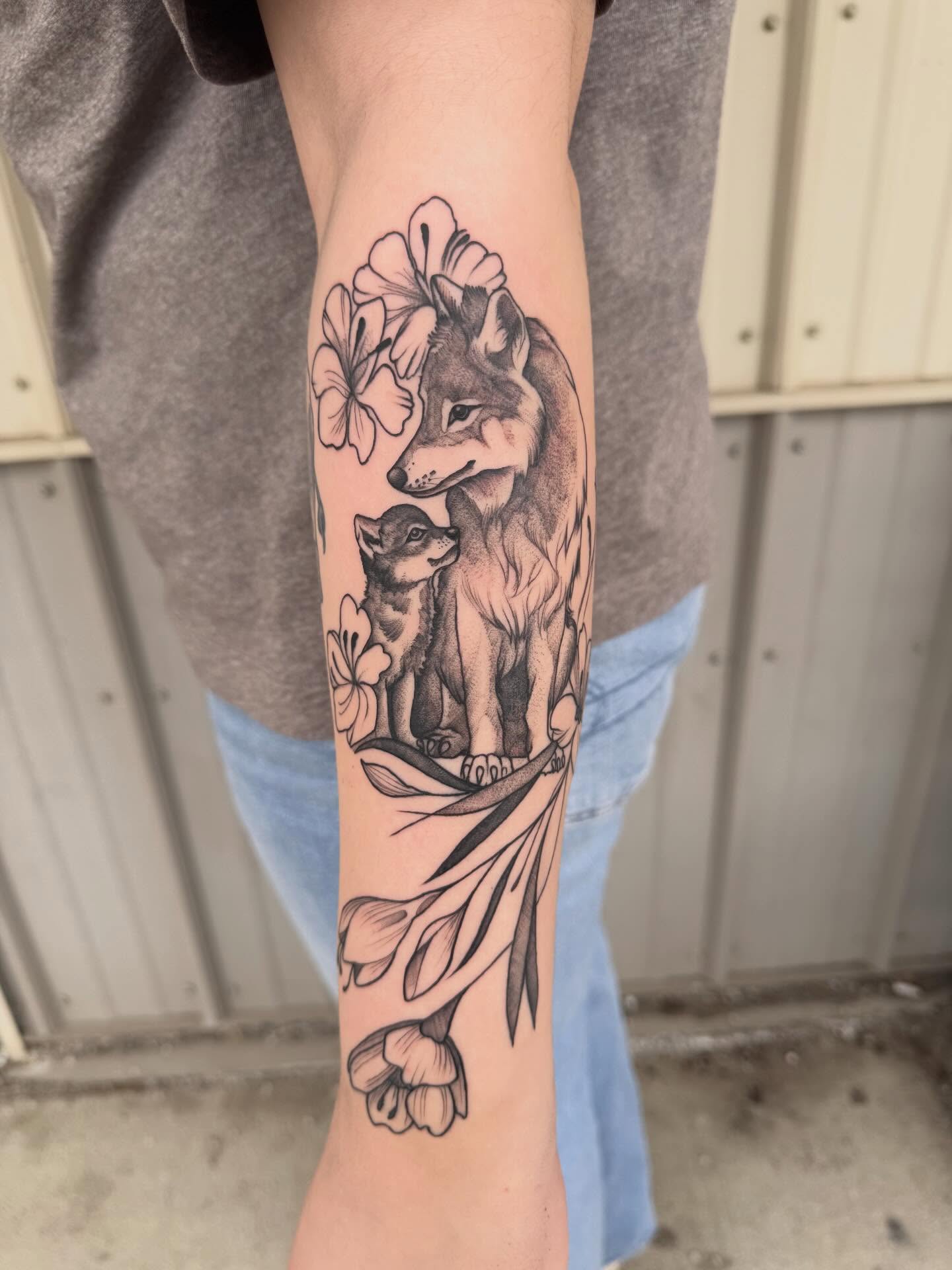 Wolf and cub black and grey tattoo on the forearm by Kayla Rosencrans