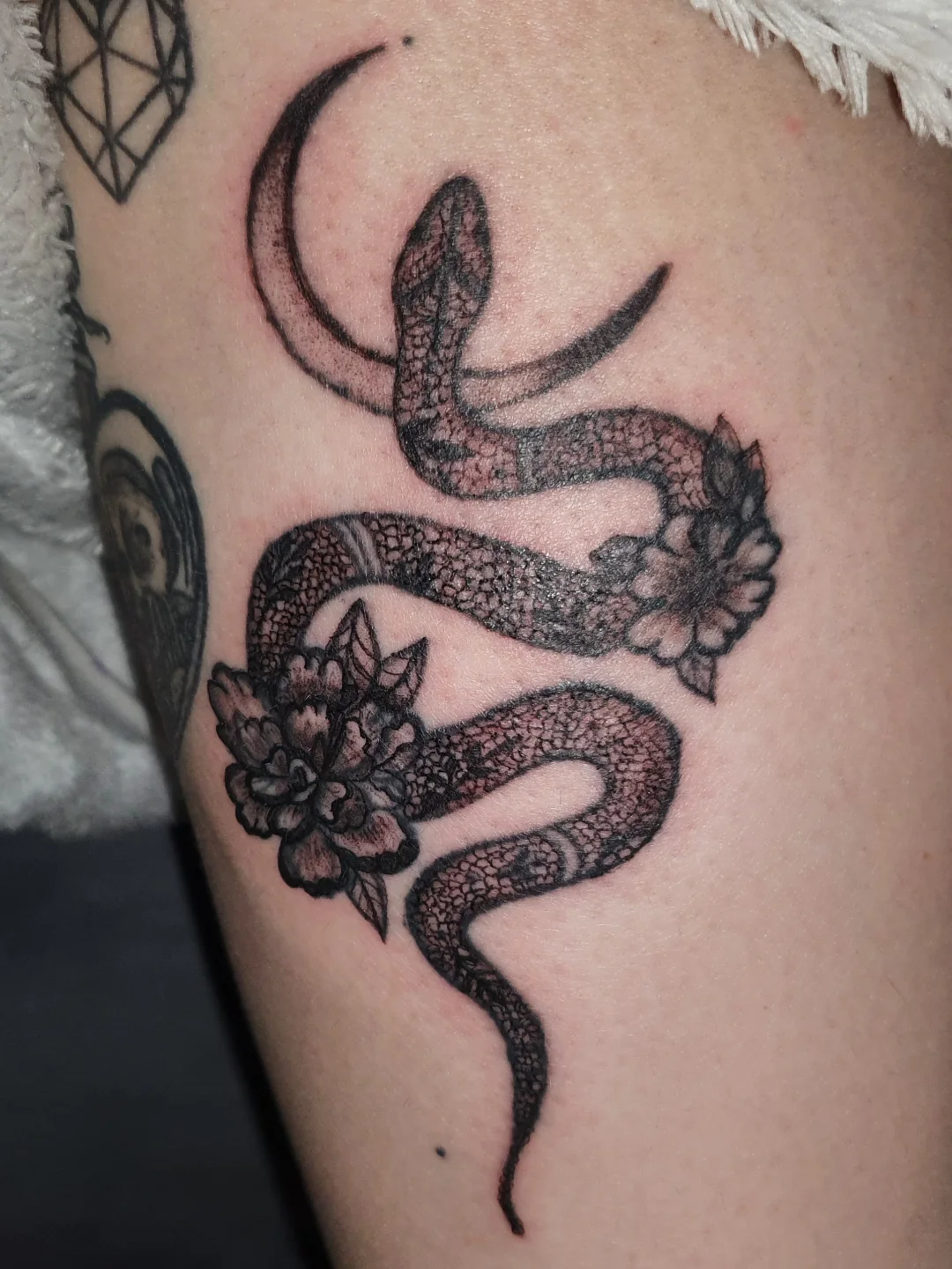 Snake and flowers black and grey tattoo on the thigh by Artful Ink