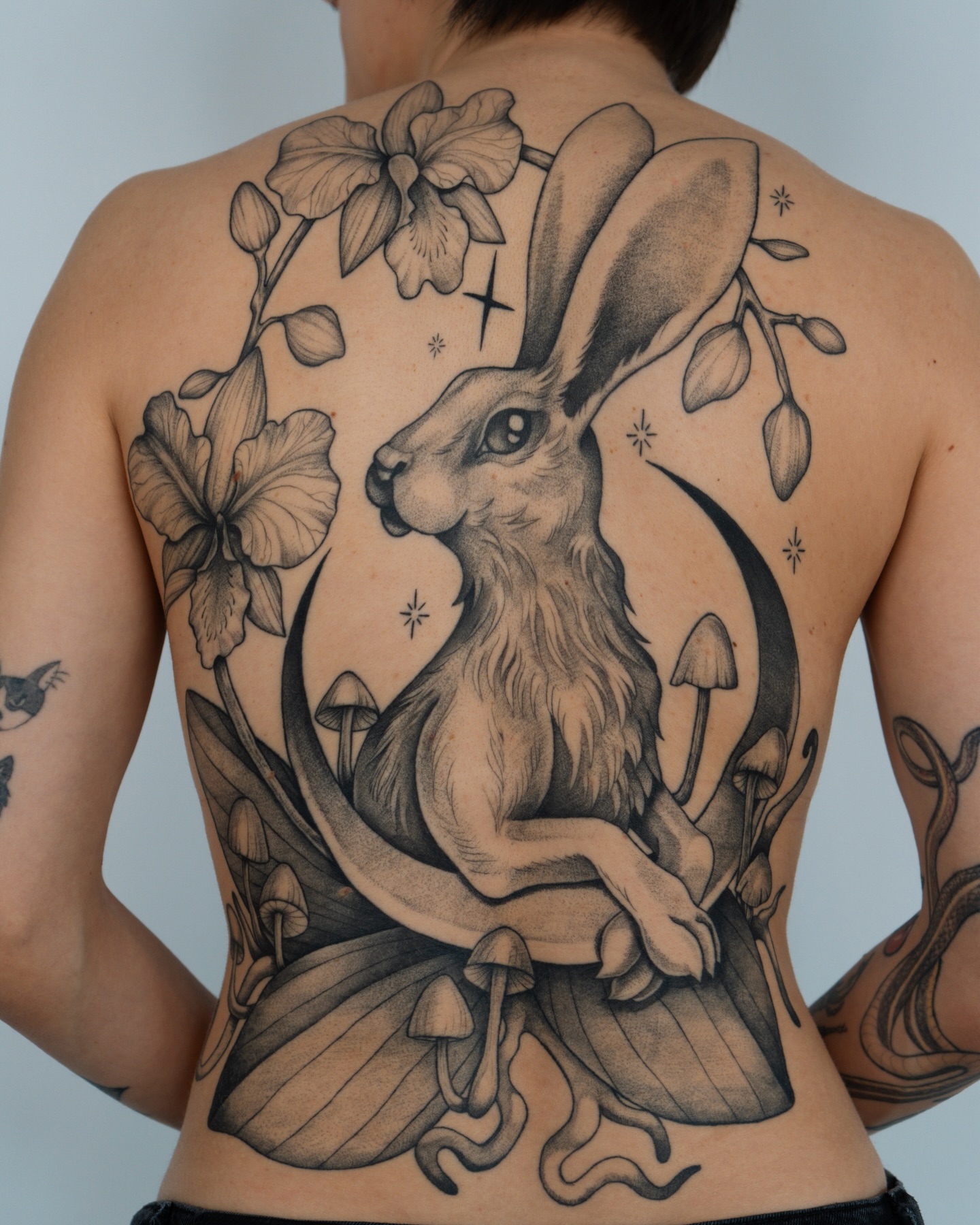 Rabbit and flowers realism tattoo on the back by Mikayla Sue