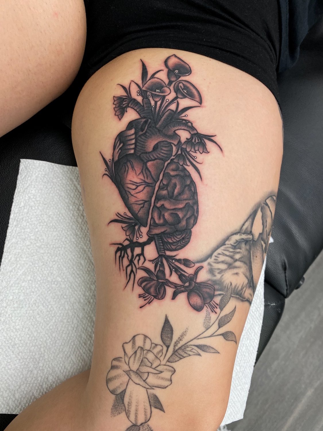 Anatomical heart with flowers realism tattoo on the thigh by Kelan Mckenna