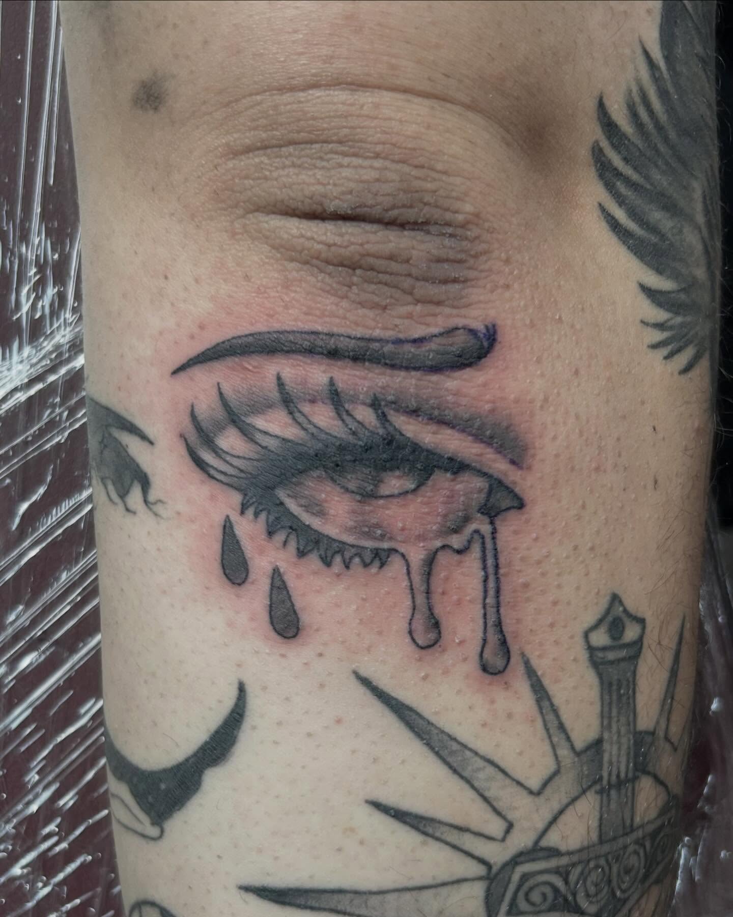 Tearful eye black and grey tattoo on the forearm by Red✨, Gansevoort, New York