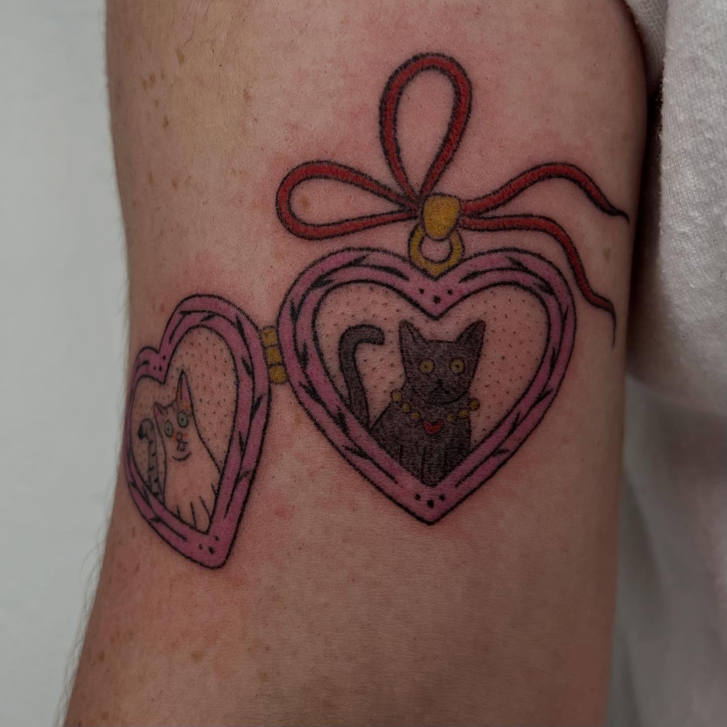 Heart-shaped locket with cats dotwork tattoo on the forearm by Jenna