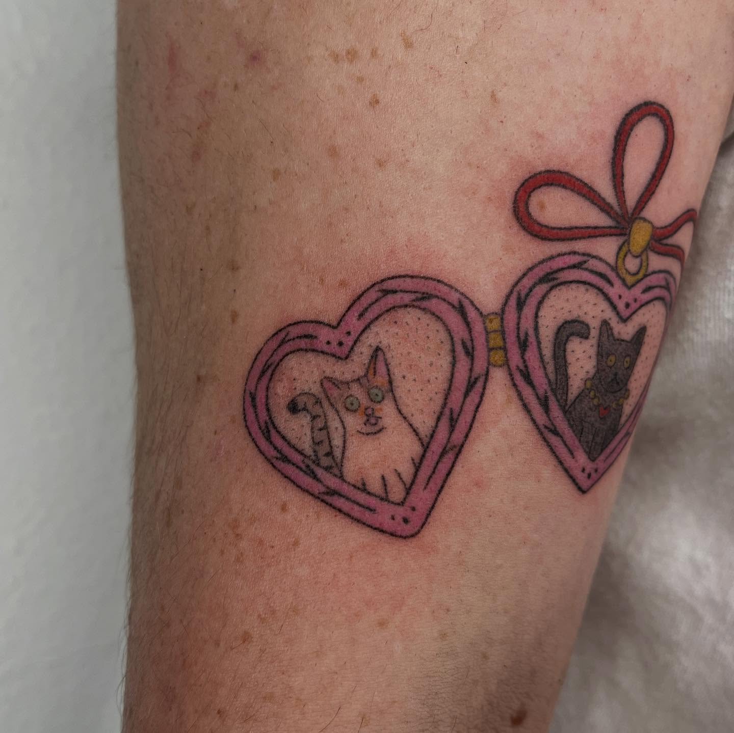 Heart-shaped locket with cats dotwork tattoo on the forearm by Jenna