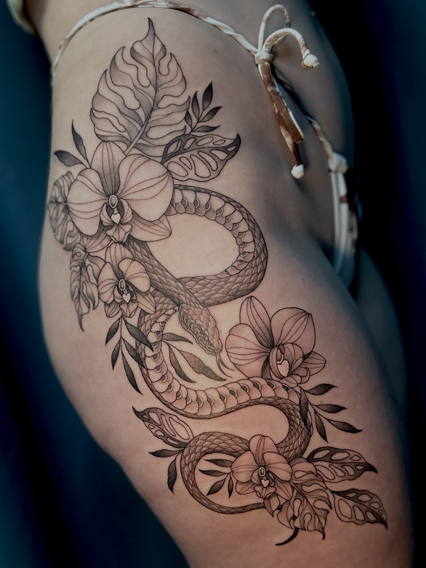 Snake and flowers ornamental tattoo on the thigh by Ghost