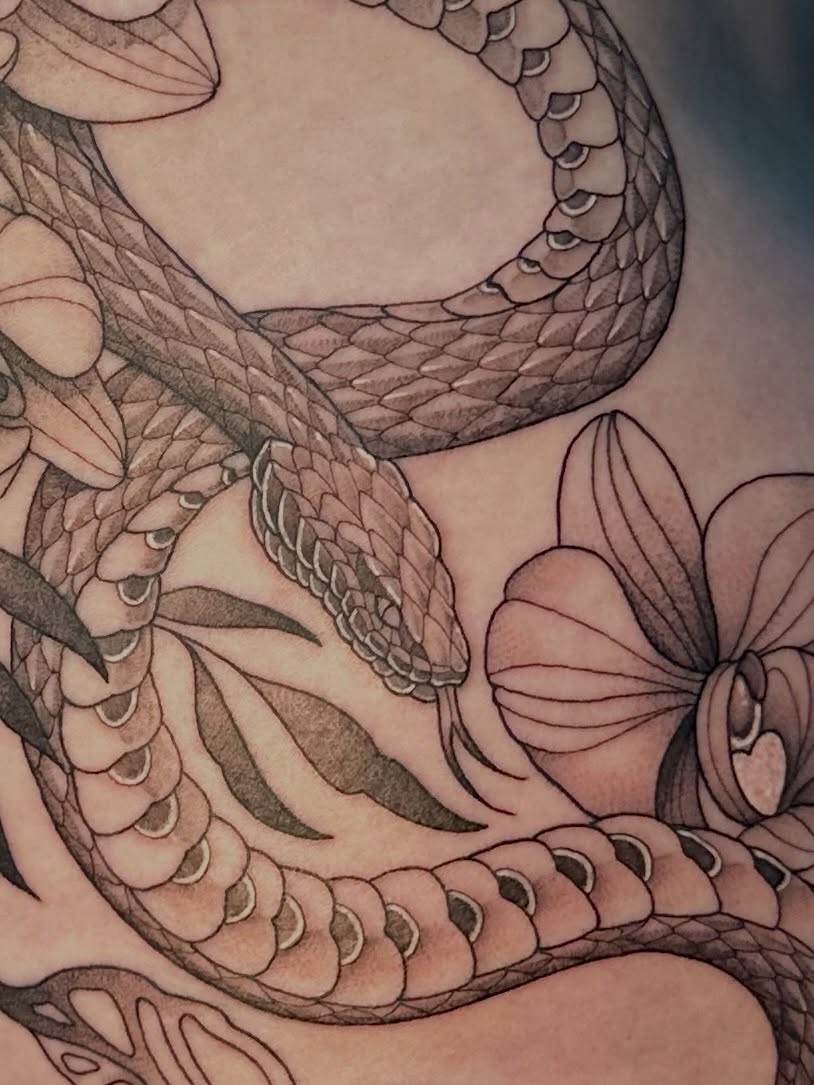 Snake and flowers realism tattoo on the torso by Ghost