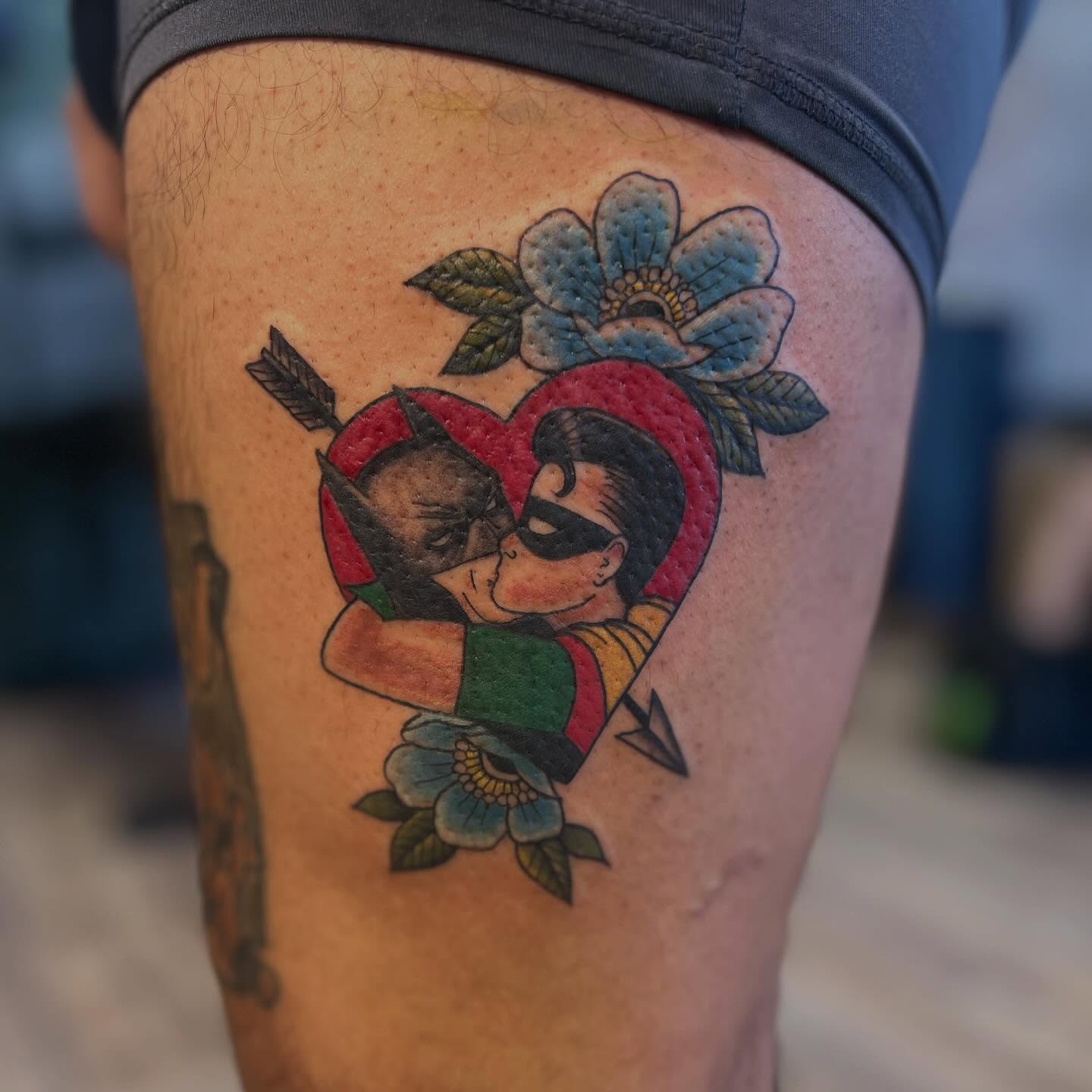 Heart with superheroes American traditional tattoo on the thigh by Victorian Coleman