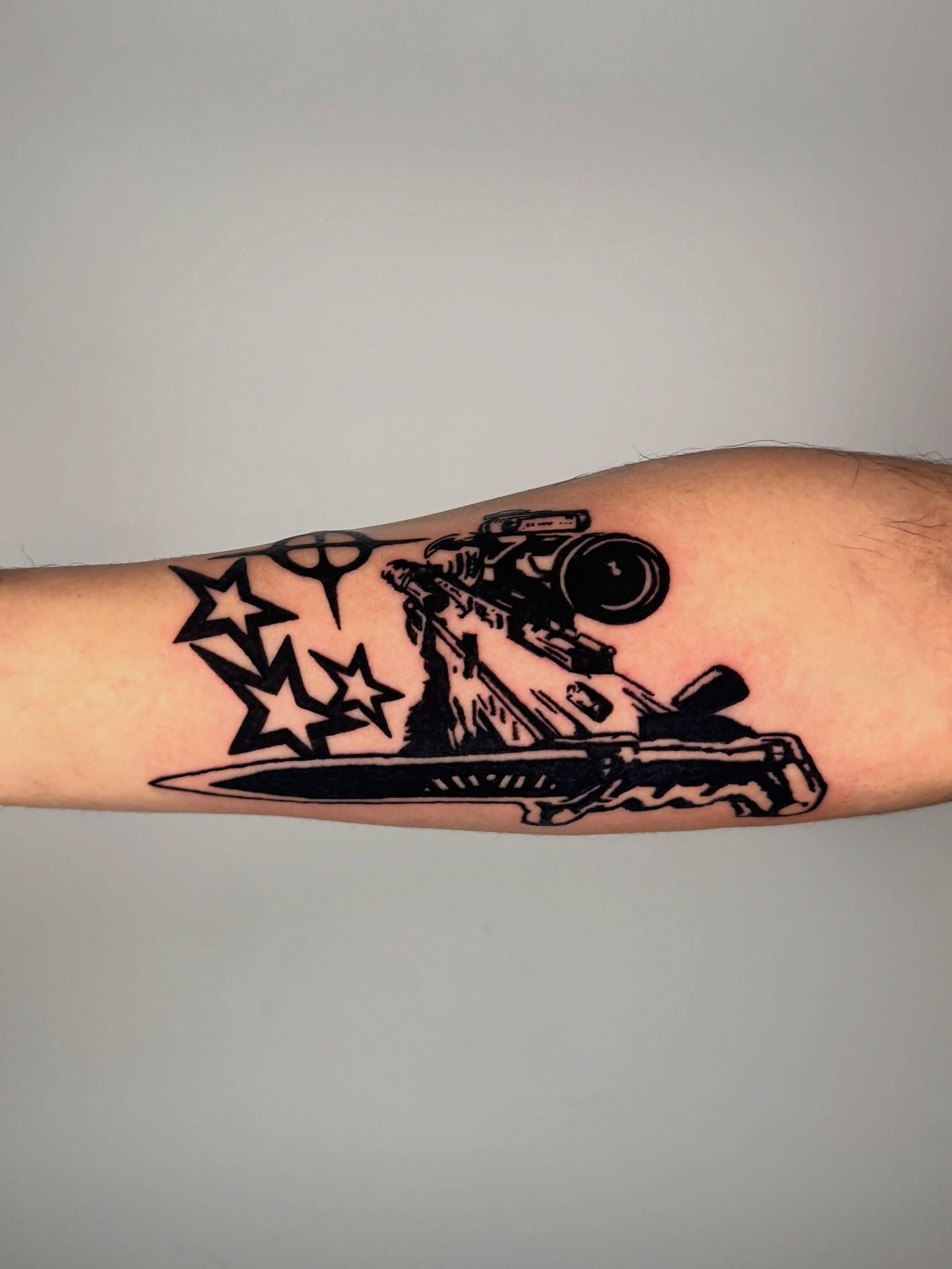 Gun and stars black and grey tattoo on the forearm by 𝔠𝔲𝔯𝔱𝔦𝔰 ~ tattoo artist