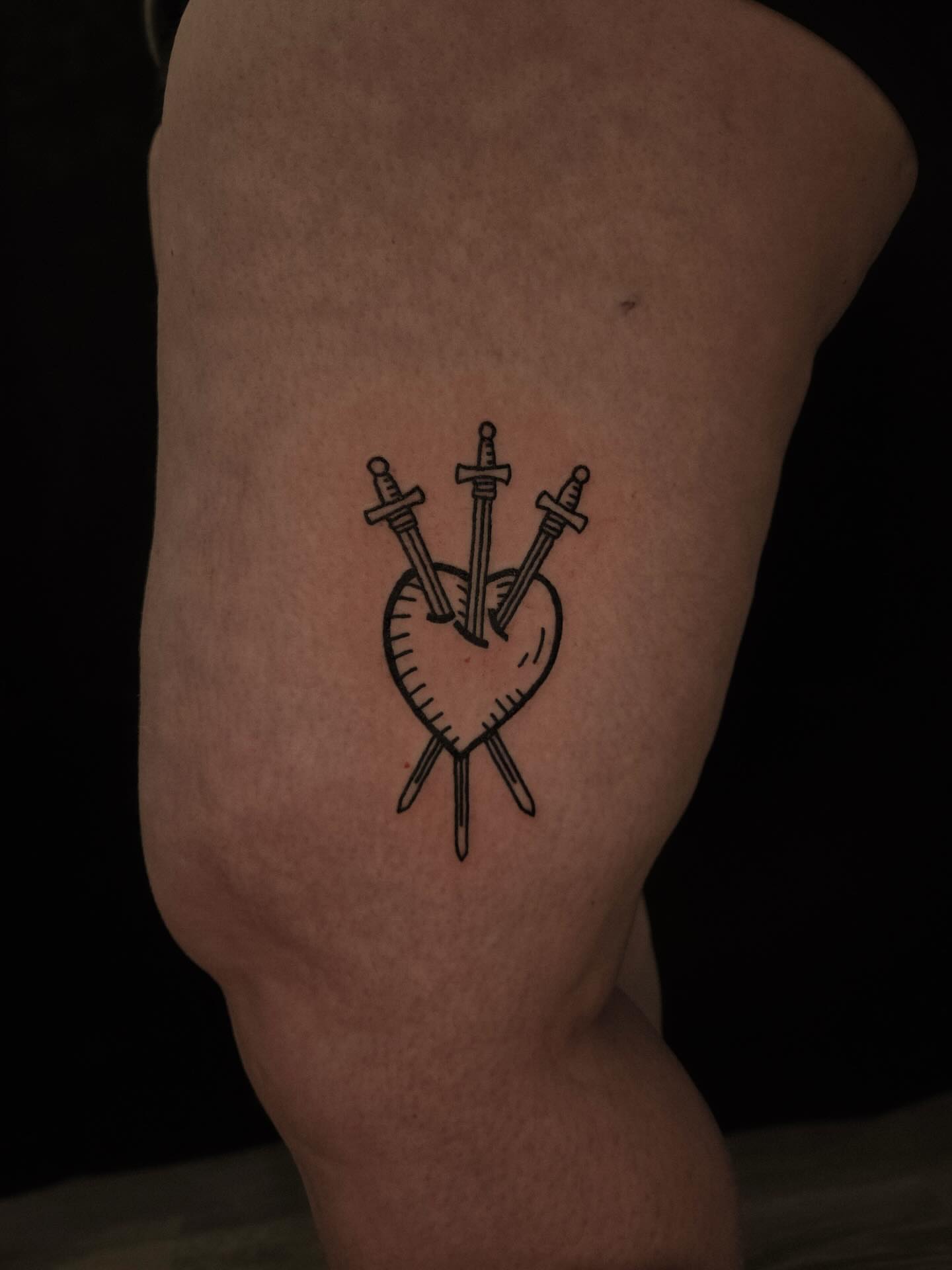 Heart with swords black and grey tattoo on the thigh by ashley blyght